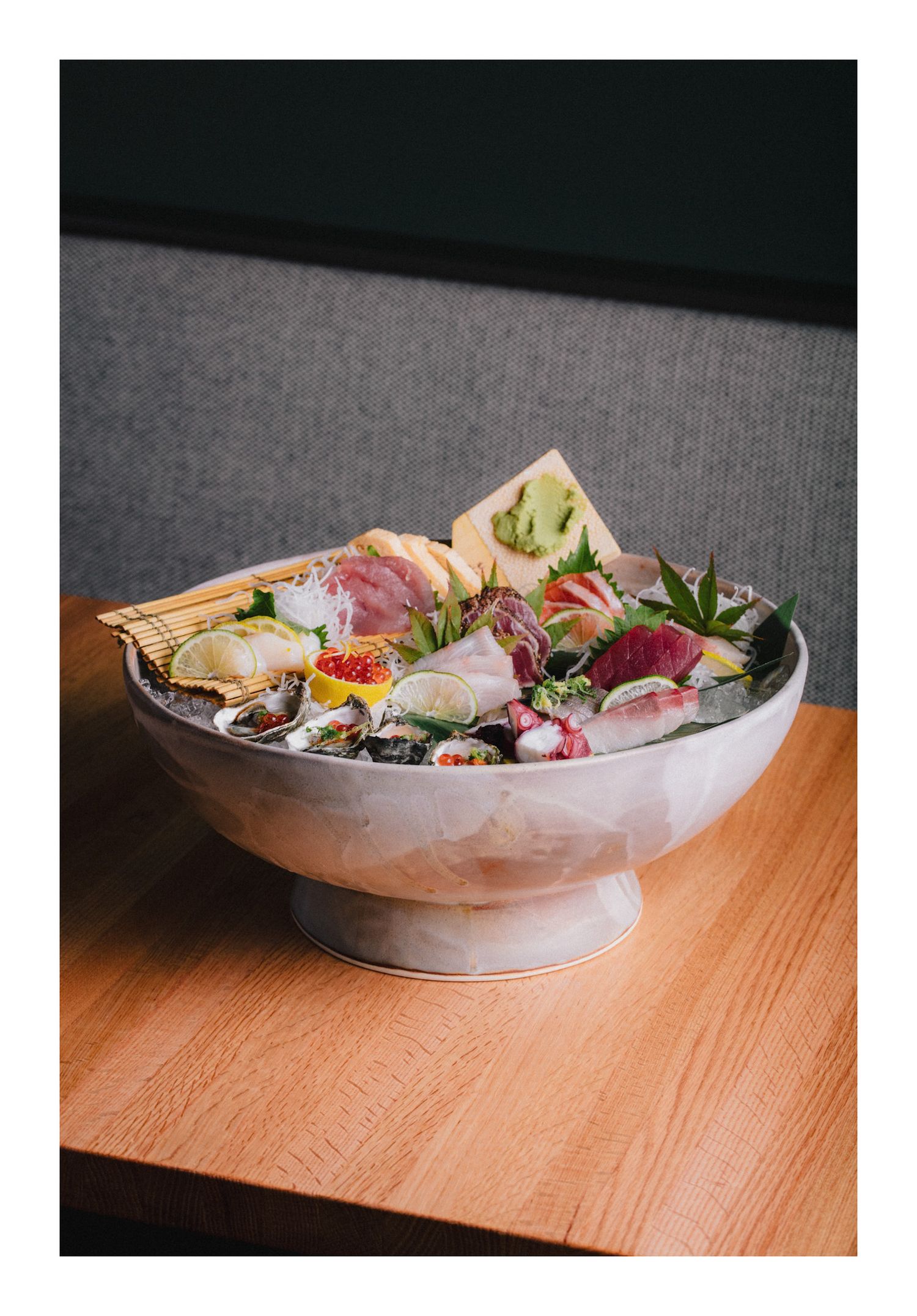 Fresh sashimi and seafood served in a chilled bowl with garnishes on a wooden table.