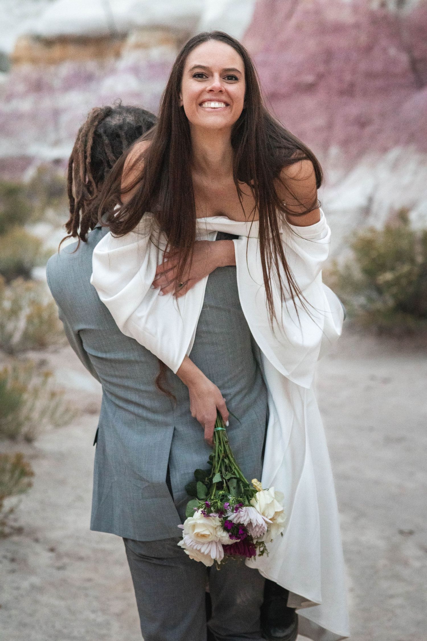 Playful piggyback moment captured during desert wedding photoshoot.