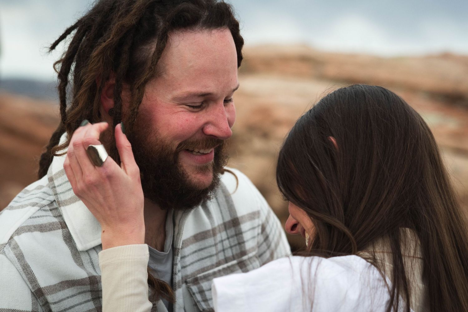 Two people sharing laughter and tender moments against a desert mountain backdrop.