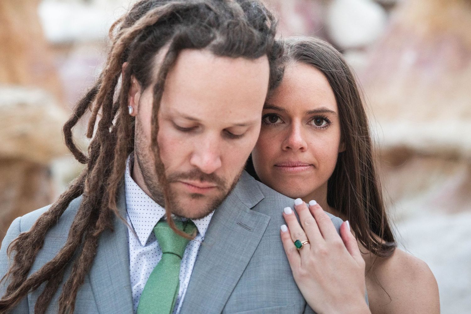 Intimate close-up portrait showcases dreadlocks and formal wedding attire.