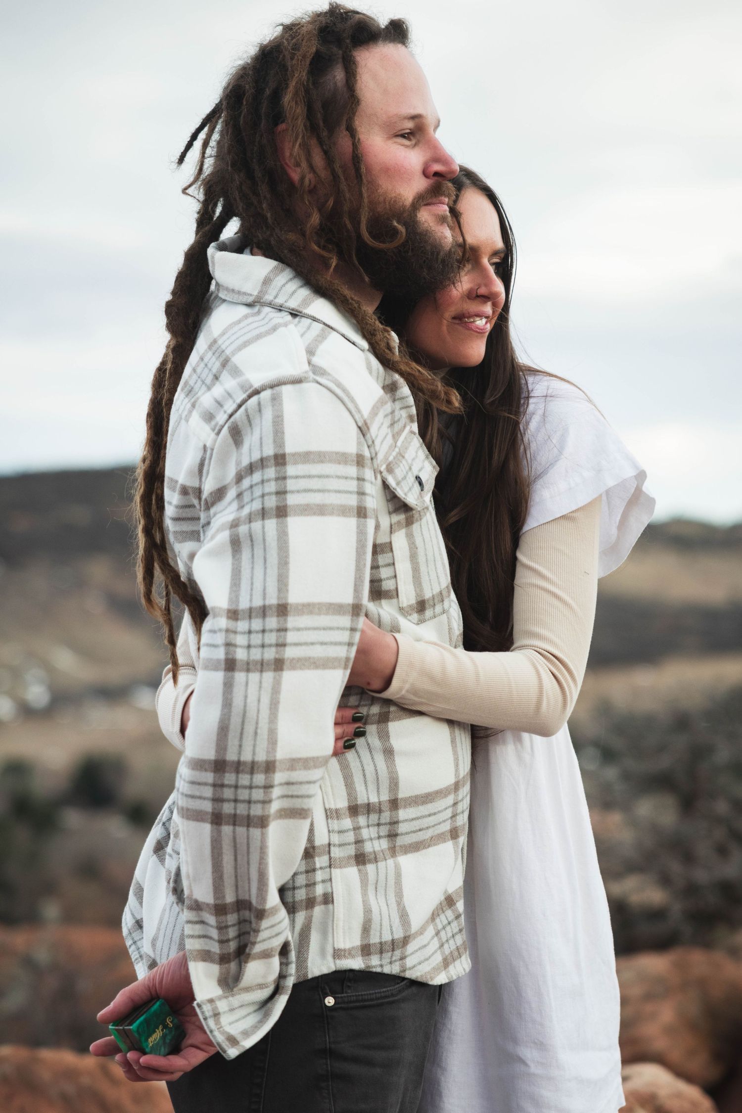 Couple shares intimate embrace against desert mountain backdrop.