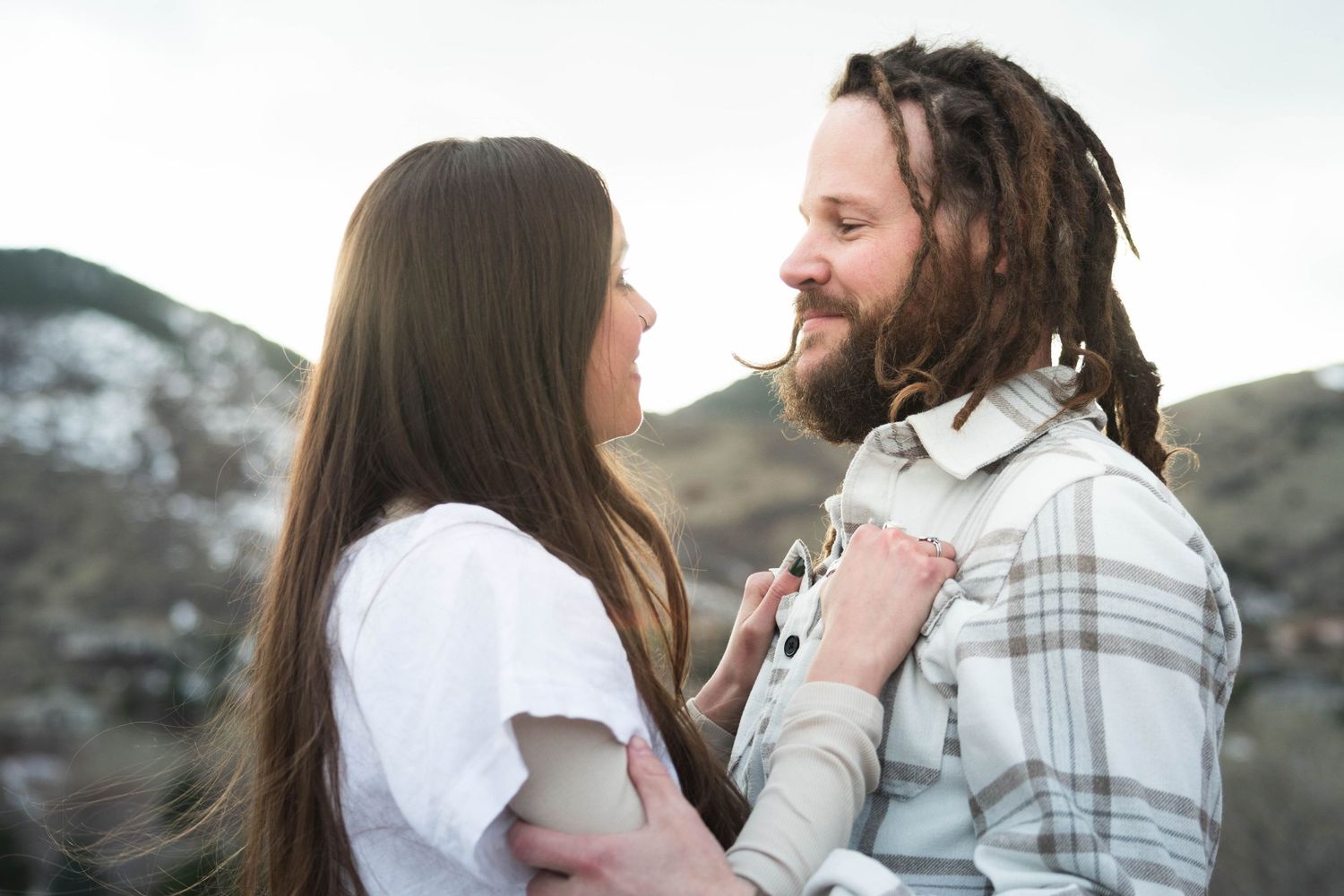 An intimate moment between two people during what appears to be a proposal in a mountainous setting.