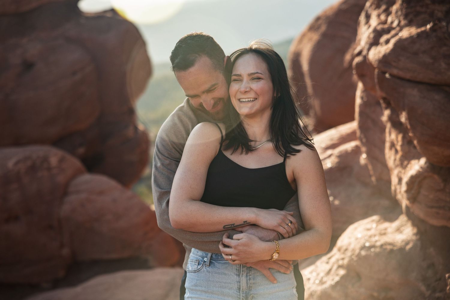 Couple sharing tender moments against red rock formations during sunset.
