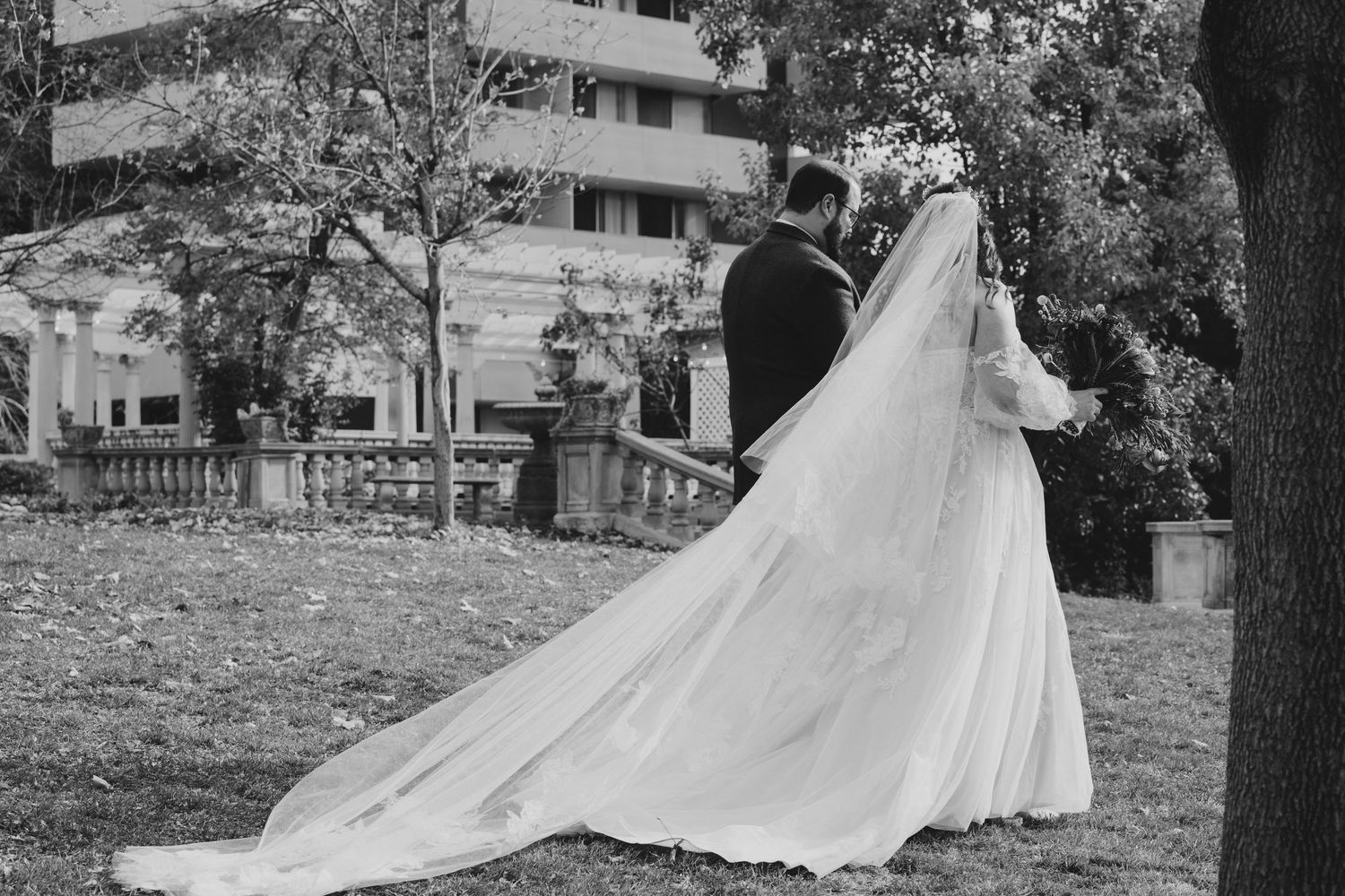 Bride in flowing white gown twirling in garden setting.