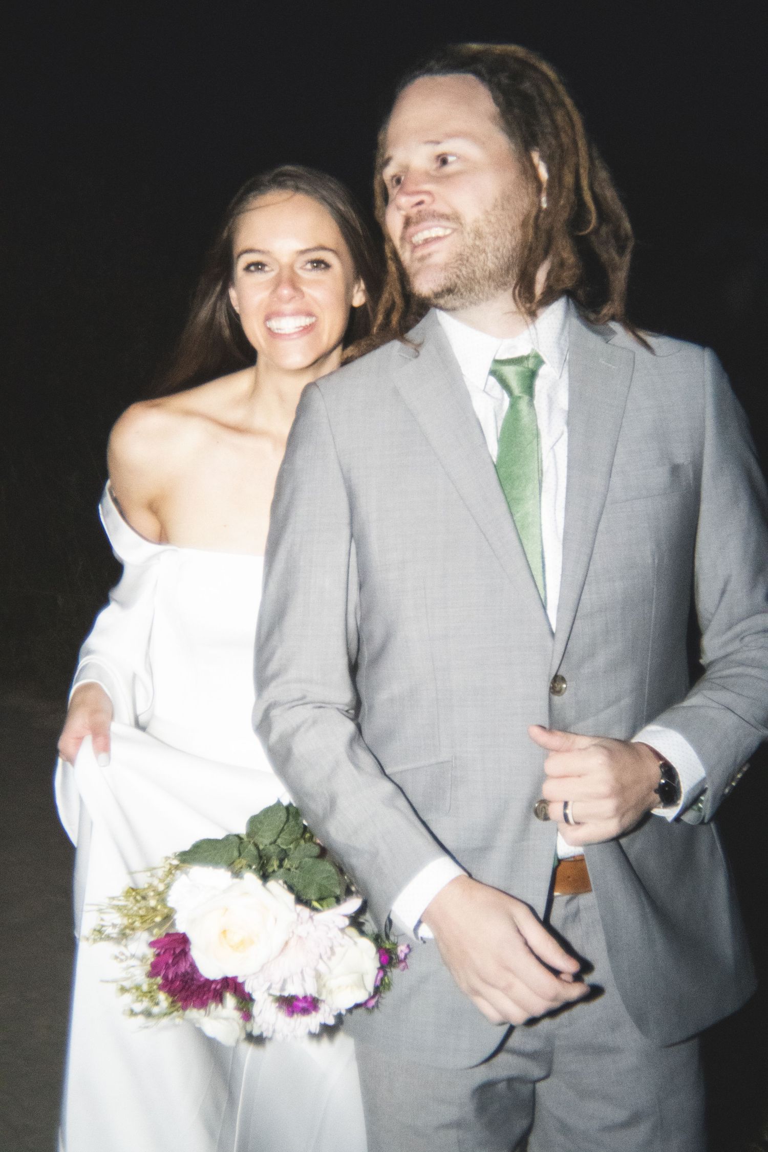 Nighttime wedding portraits showing couple in gray suit and white dress with floral bouquet.