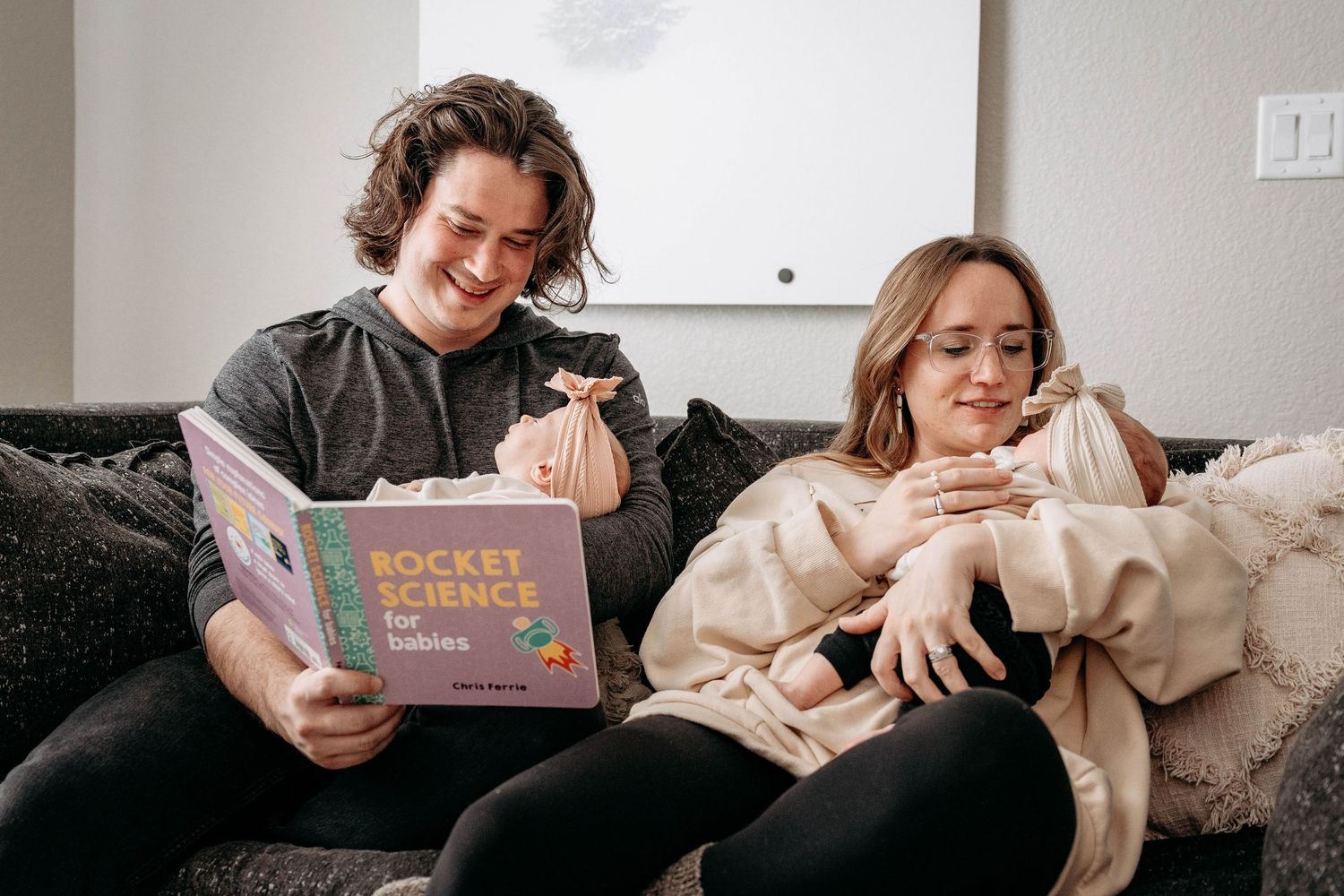Two people relax on a couch while reading a children's book together.
