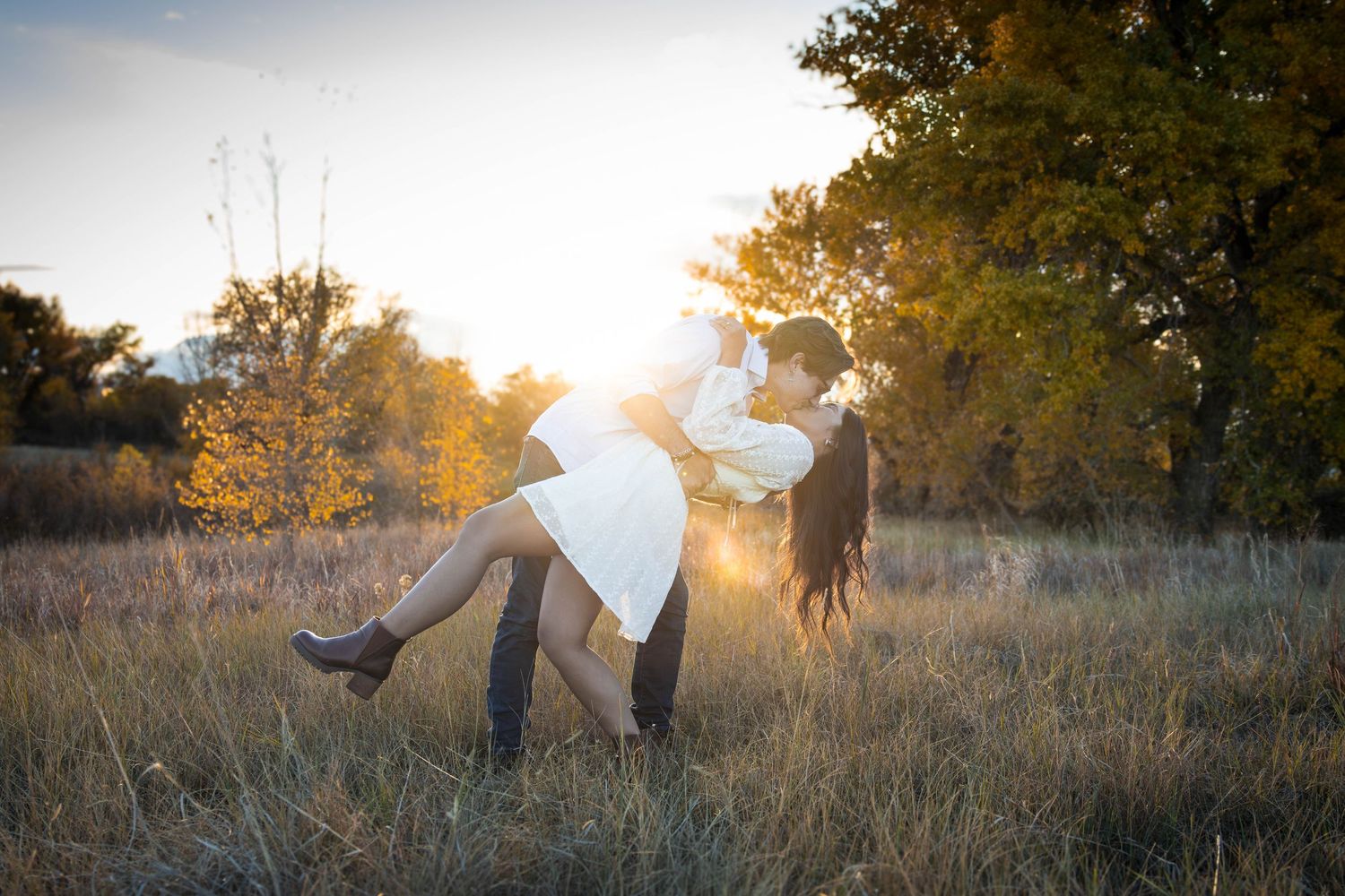 Golden hour engagement photos in tall grass field with dreamy sunlight.