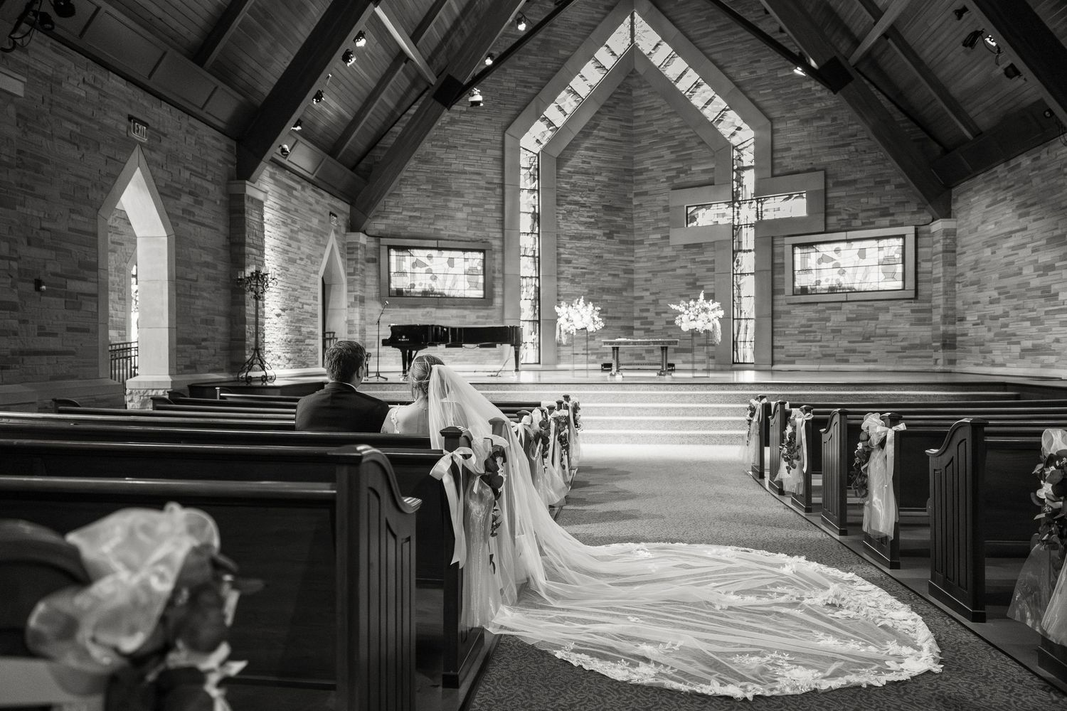 Black and white church interior with wedding veil trailing down the aisle toward the altar.