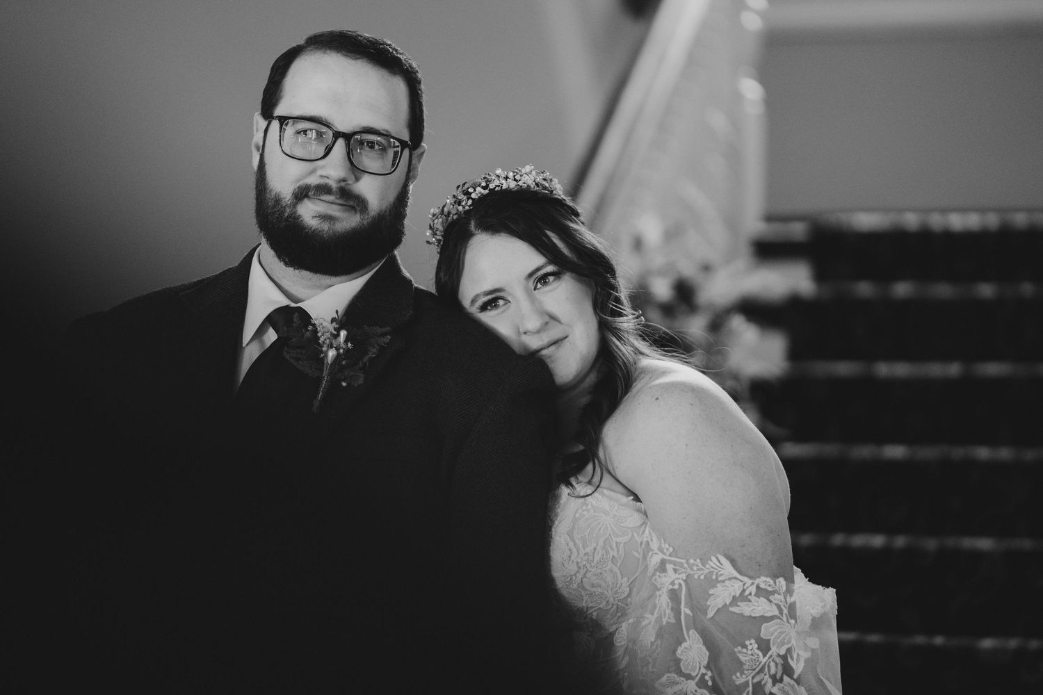 Classic black and white wedding portrait featuring formal attire and architecture.