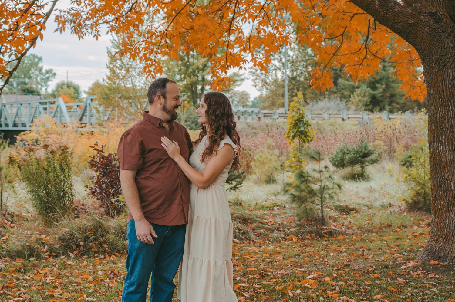 A tender moment between a couple under orange fall foliage.