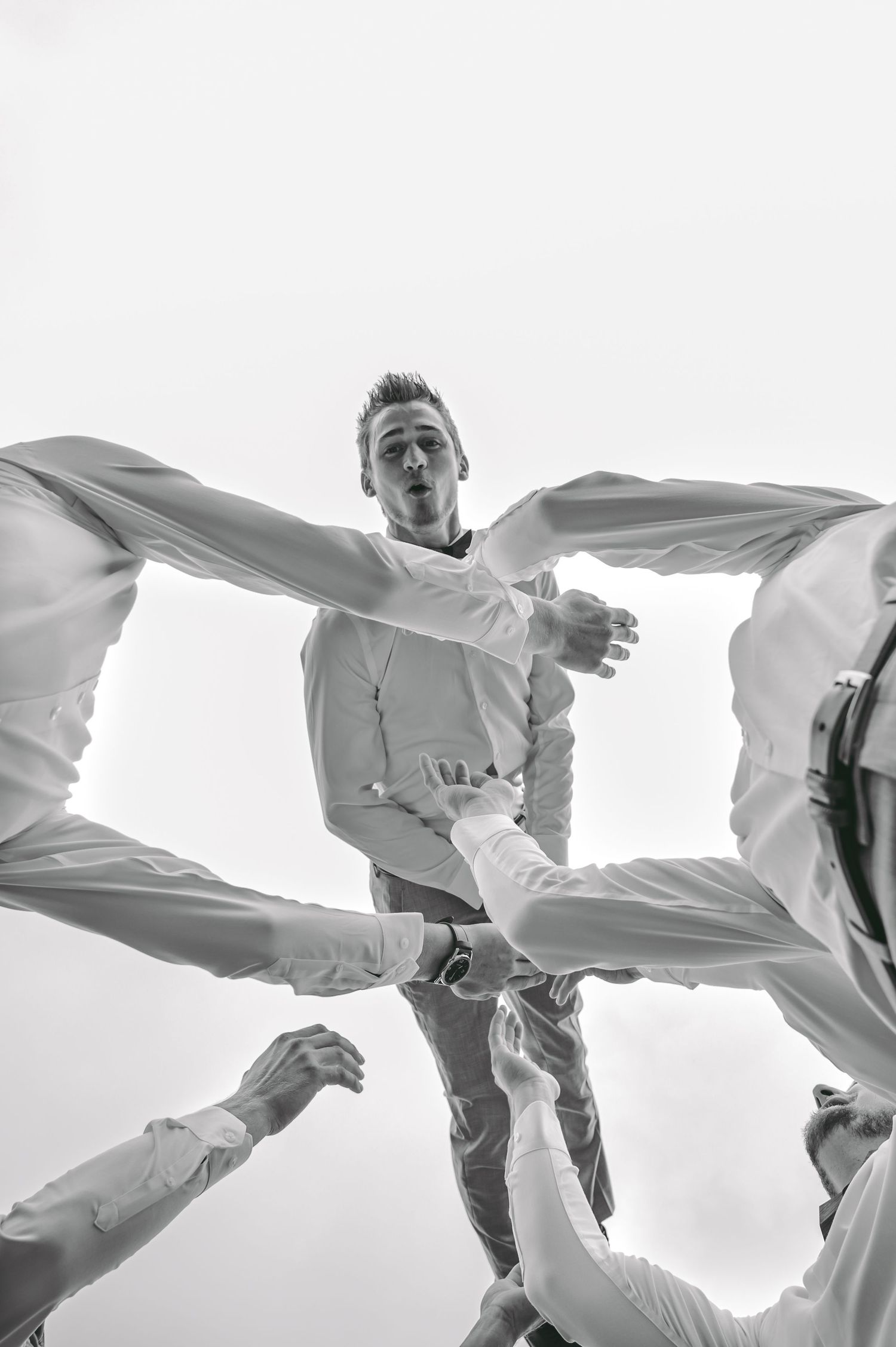 Artistic black and white of a groom being tossed in the air by his groomsmen.