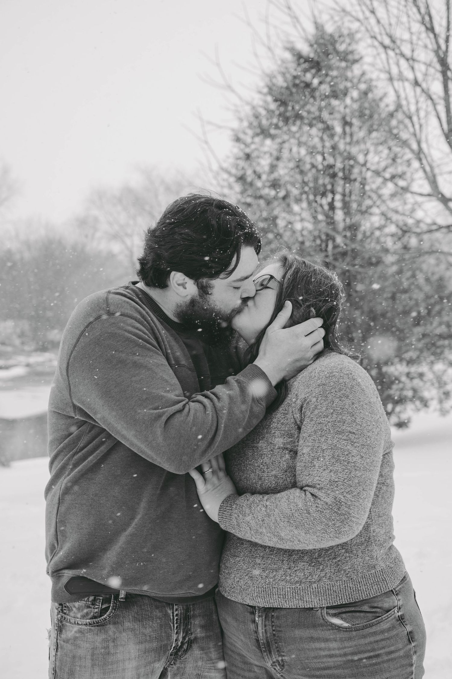 A romantic winter moment captured in black and white as a couple shares an intimate kiss in the snow.