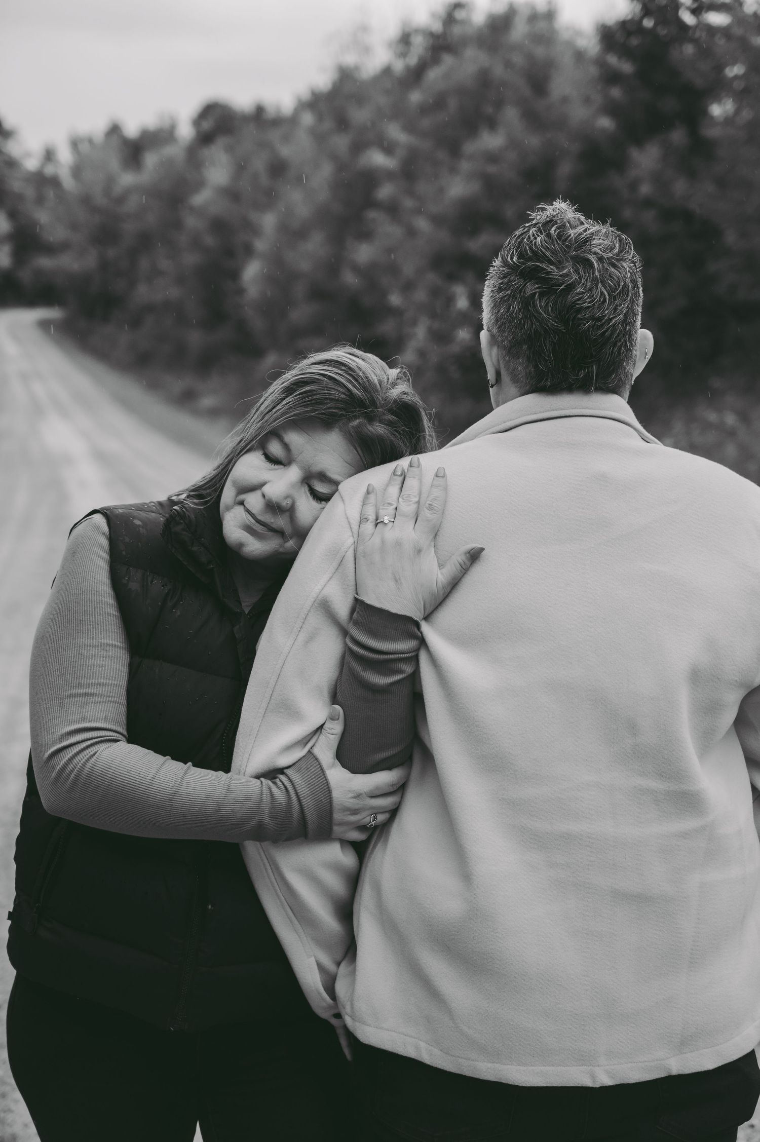 An intimate black and white photo showing a tender embrace on a country road.