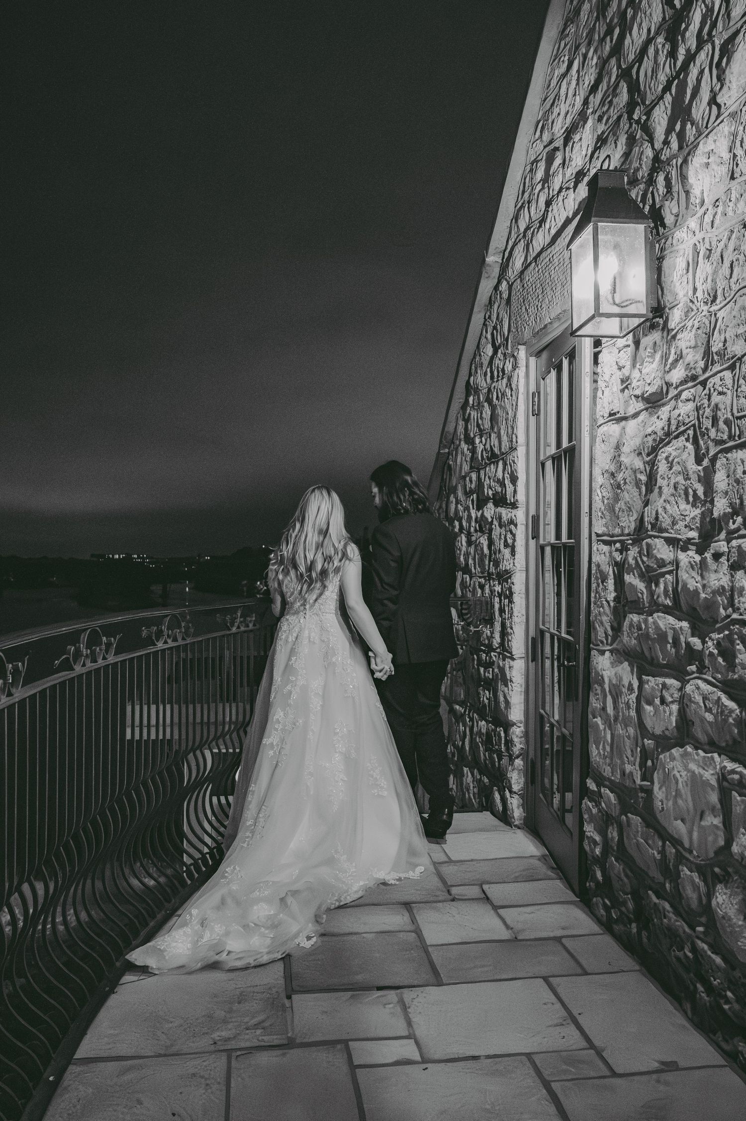 A dramatic black and white series of images showing a bride in a flowing gown on a stone balcony at the Cambridge Mill at night.