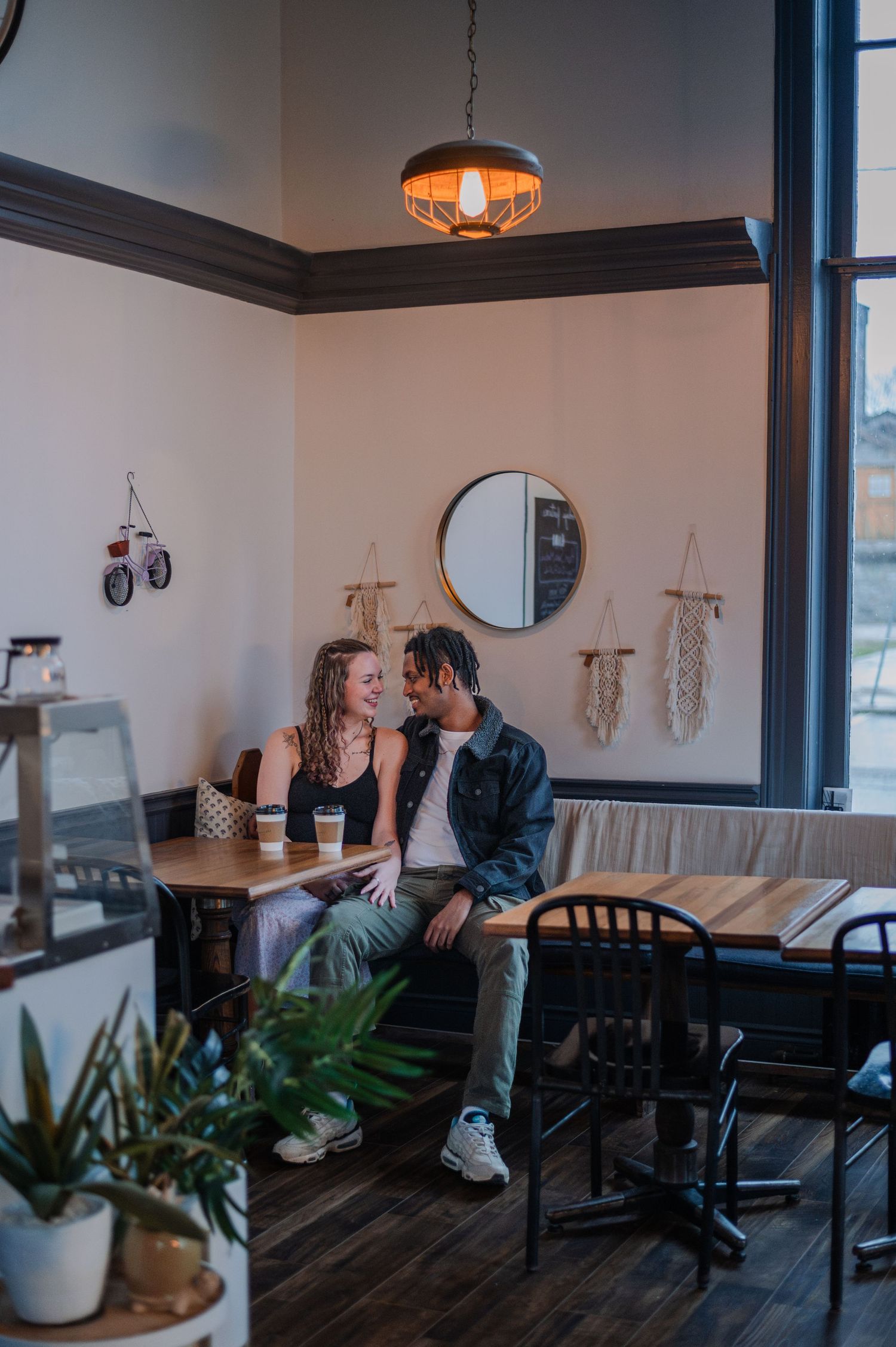 A couple shares an intimate moment at a cozy cafe booth, surrounded by warm lighting and modern decor.