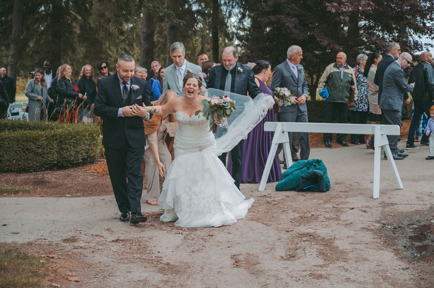 Joyful moment from outdoor wedding ceremony with attendees and stone pathway.