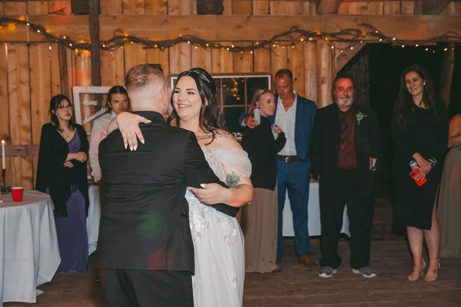 Candid celebration moments during a nighttime wedding reception in a wooden barn setting.