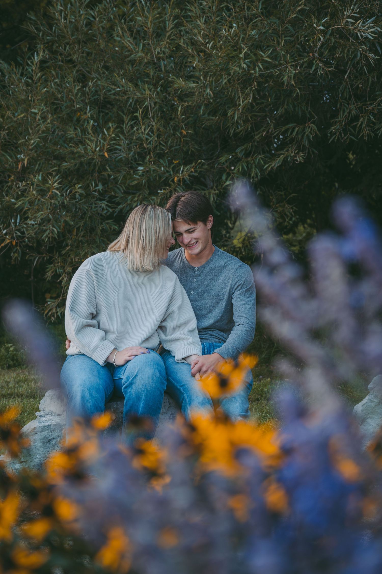 A candid moment of a couple laughing together surrounded by purple and yellow flowers.