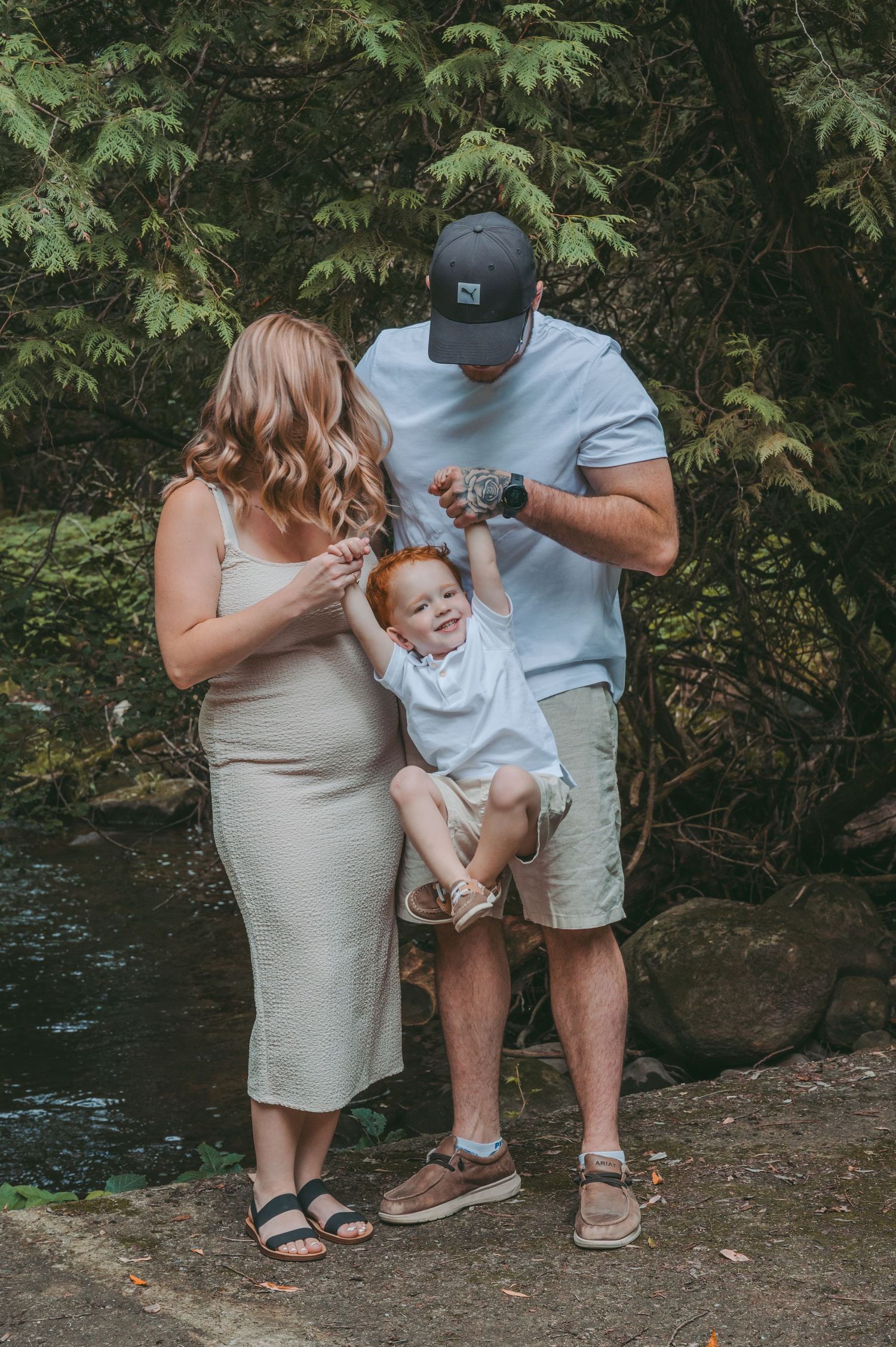 Parents playing with their baby in a natural forest setting.