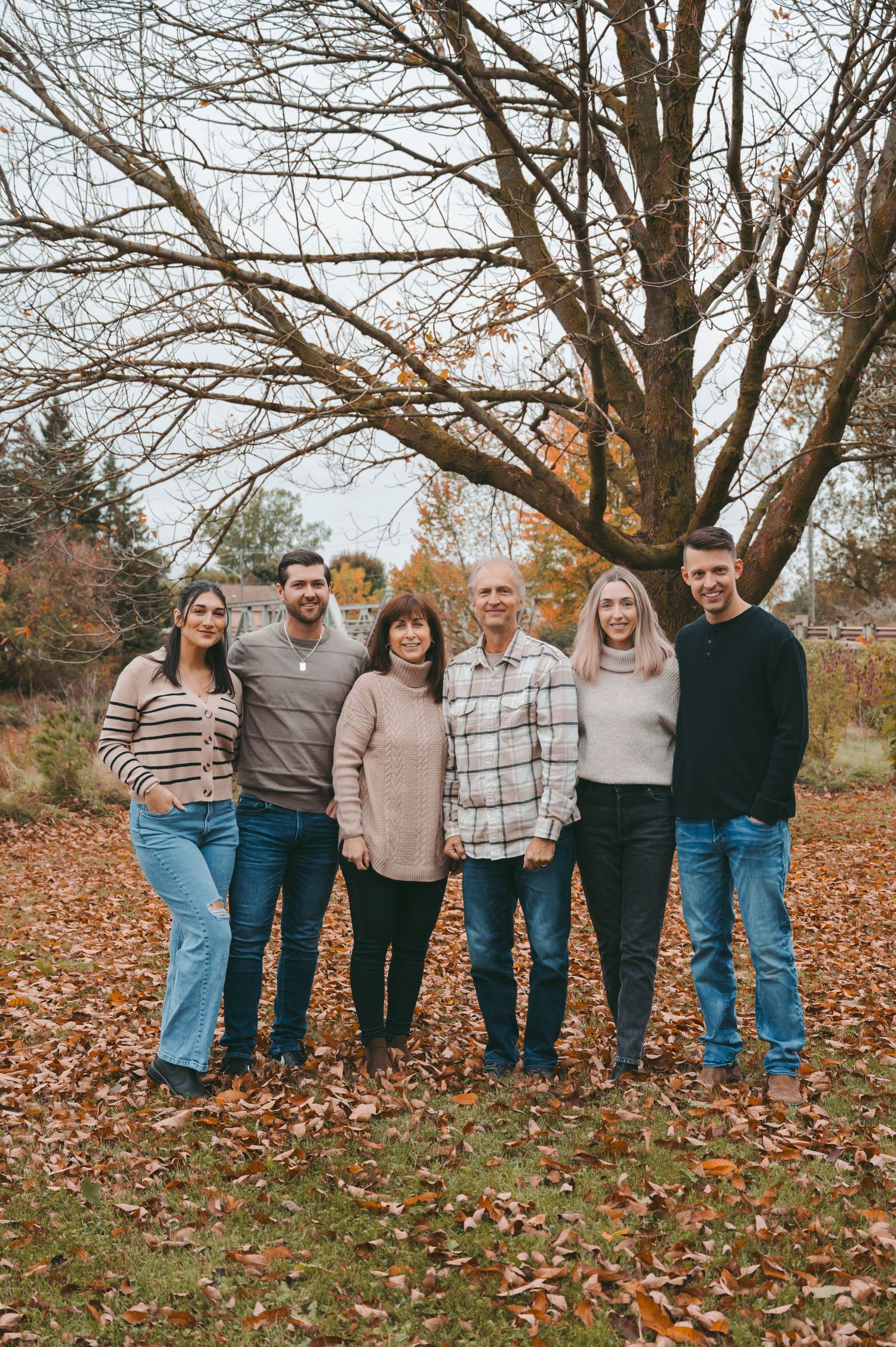 Multi-generational family poses together for a photo among fall leaves.