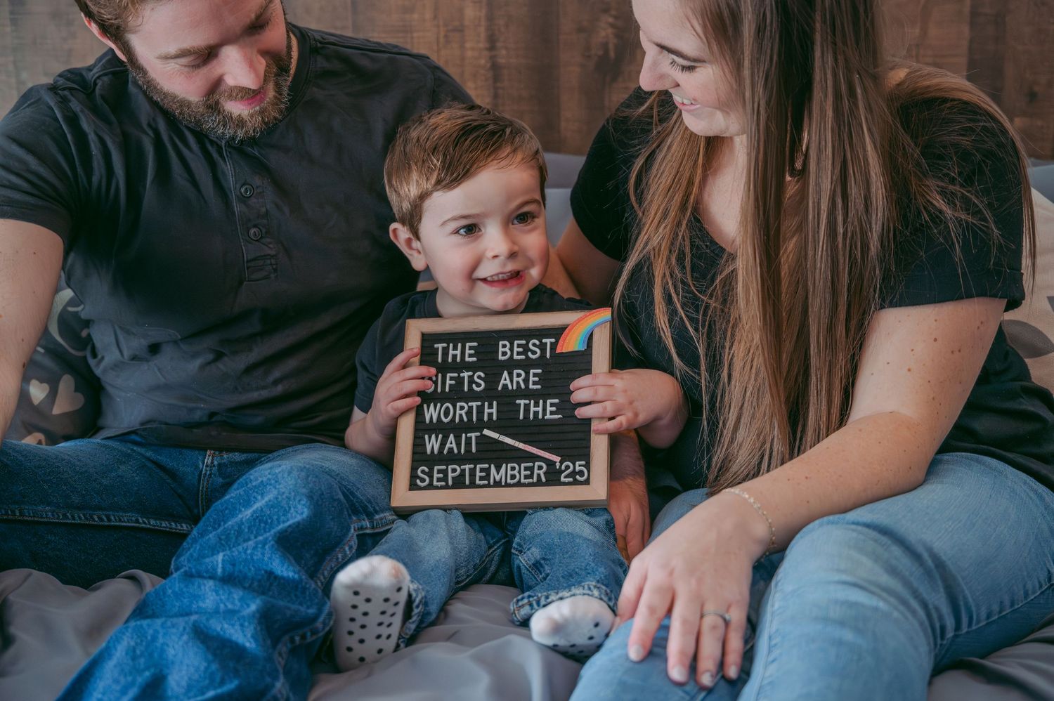 Family moment on couch with small child holding message board.
