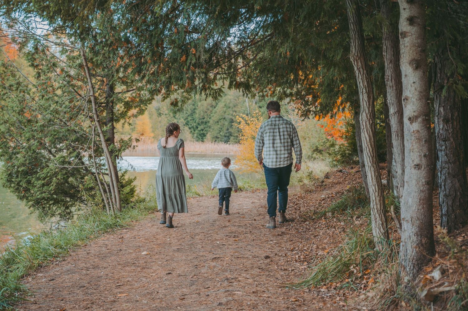 Family walking along a tree-lined path during autumn season.