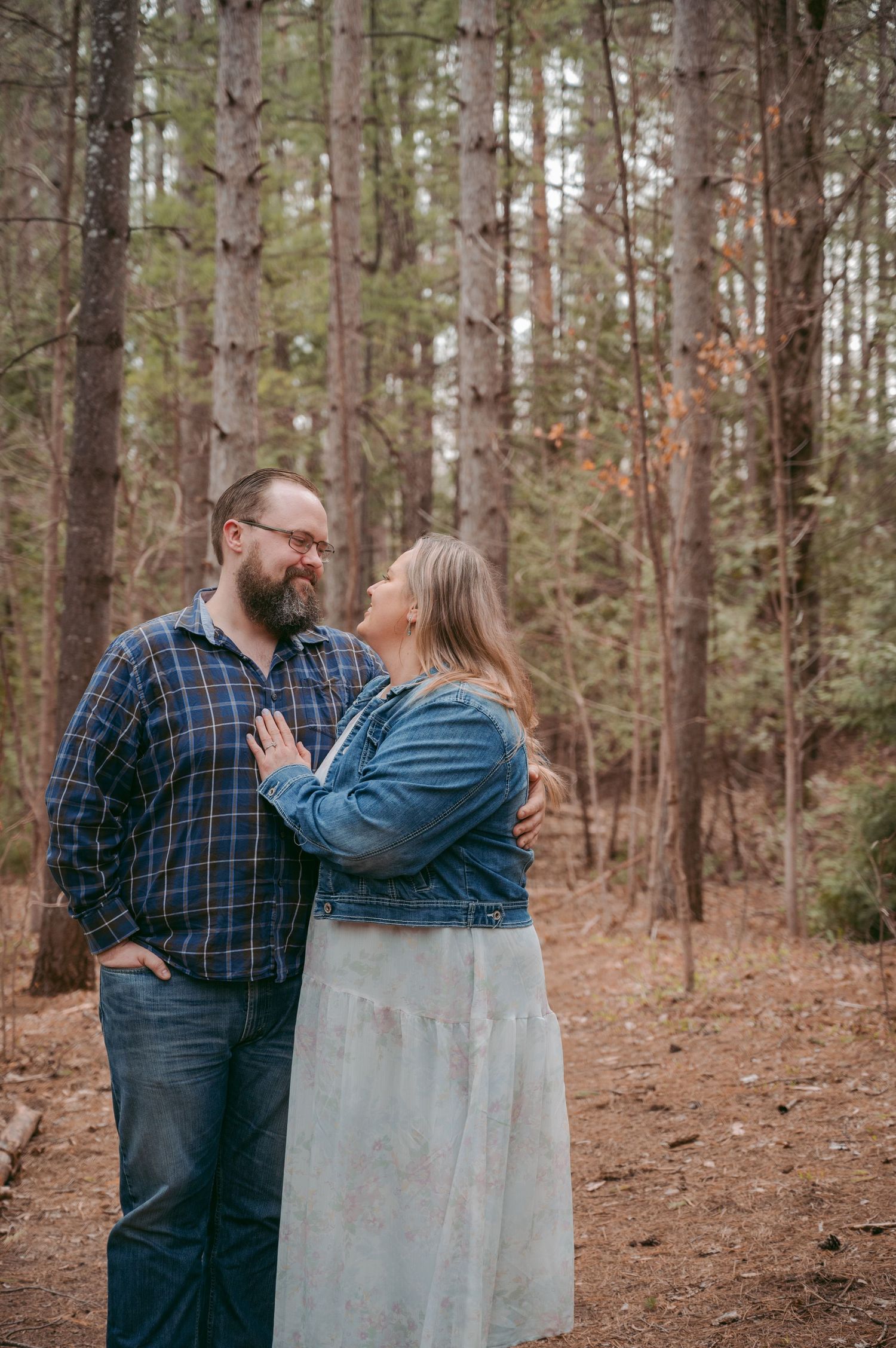 Couple sharing romantic moment in pine forest setting.