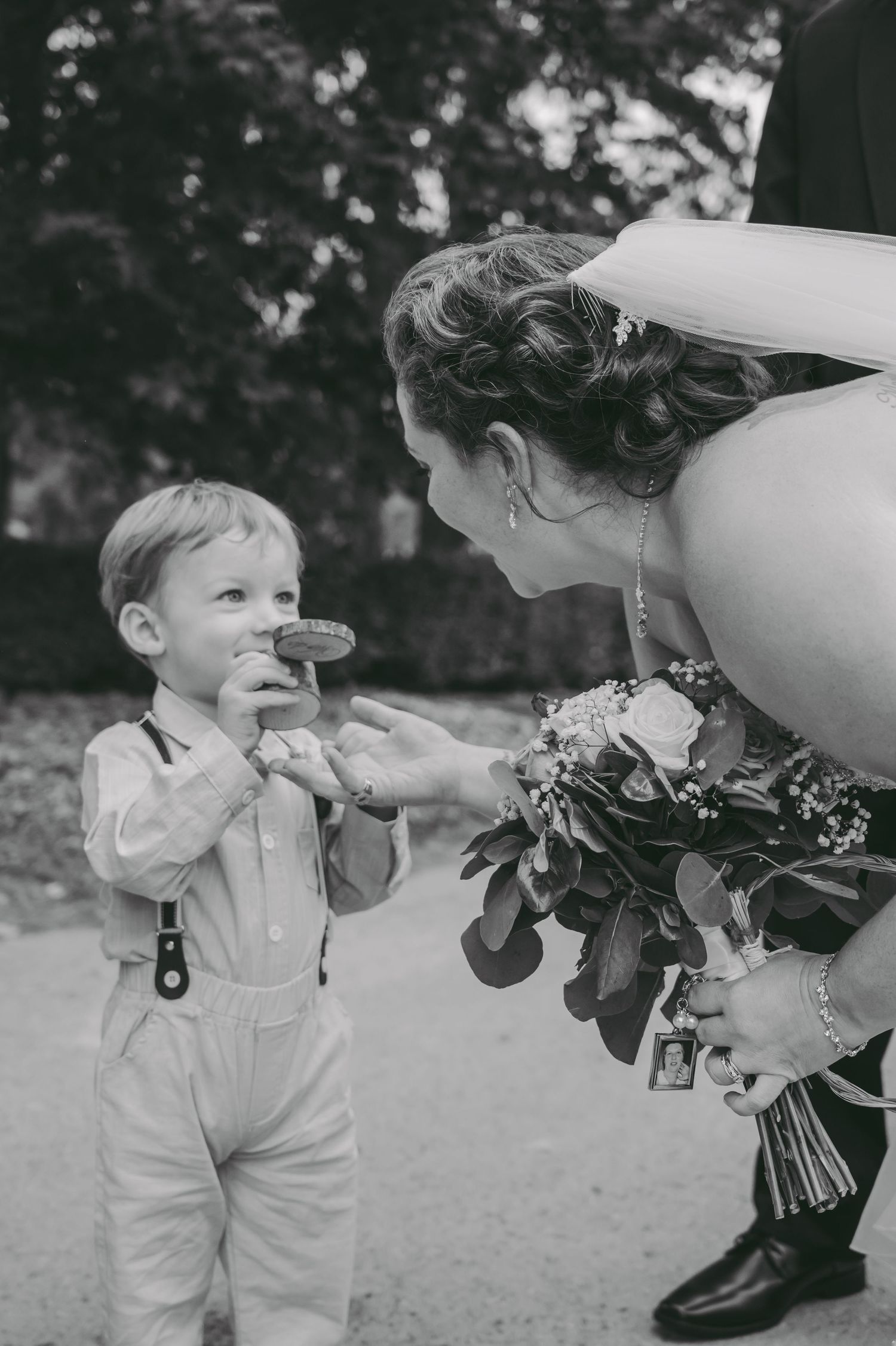 Sweet black and white moment between bride and young ring bearer at outdoor wedding.