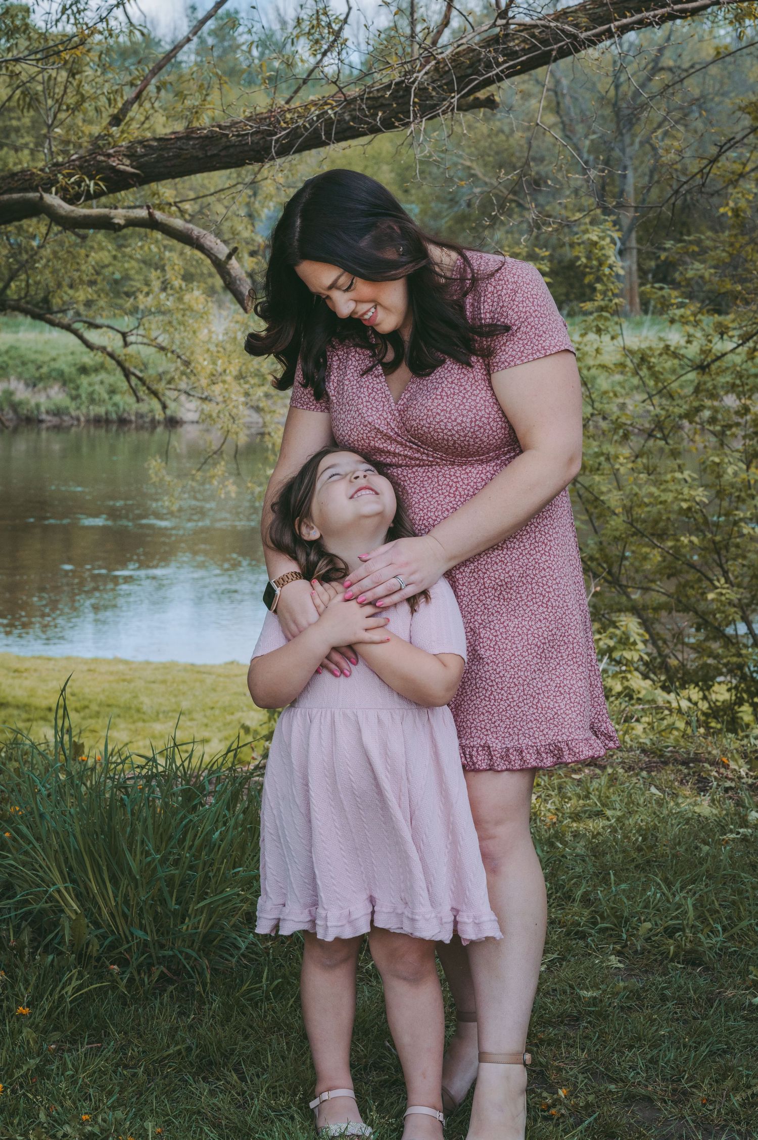 Sweet moment between parent and child embracing by a lake in spring.
