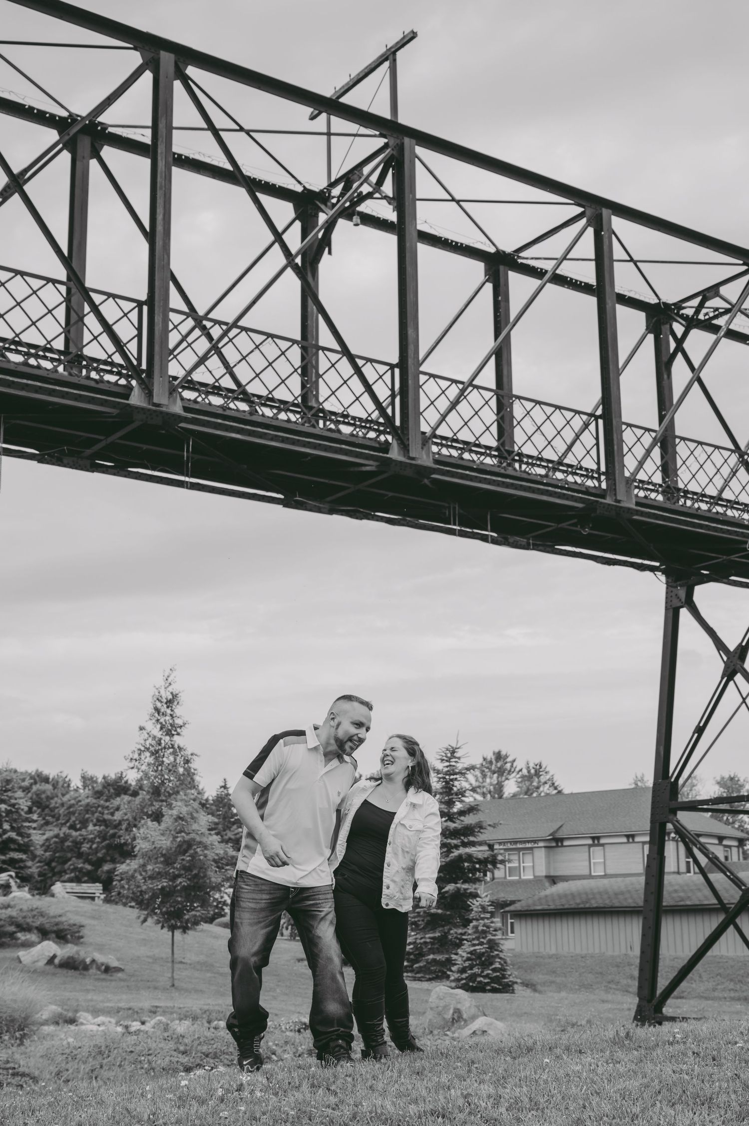 A couple sharing a tender moment beneath an industrial bridge structure.