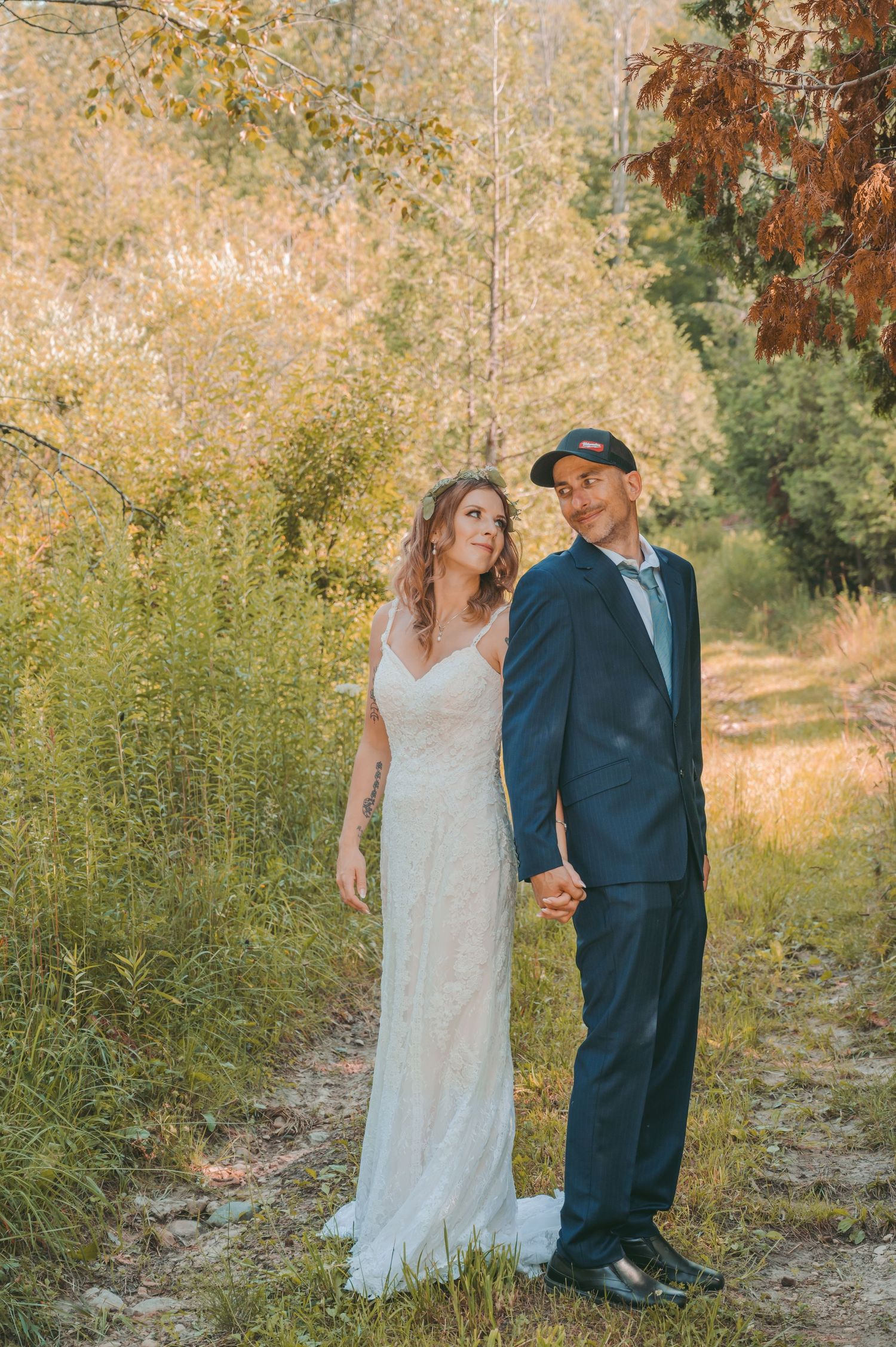 Bride and groom pose together on nature path during autumn.