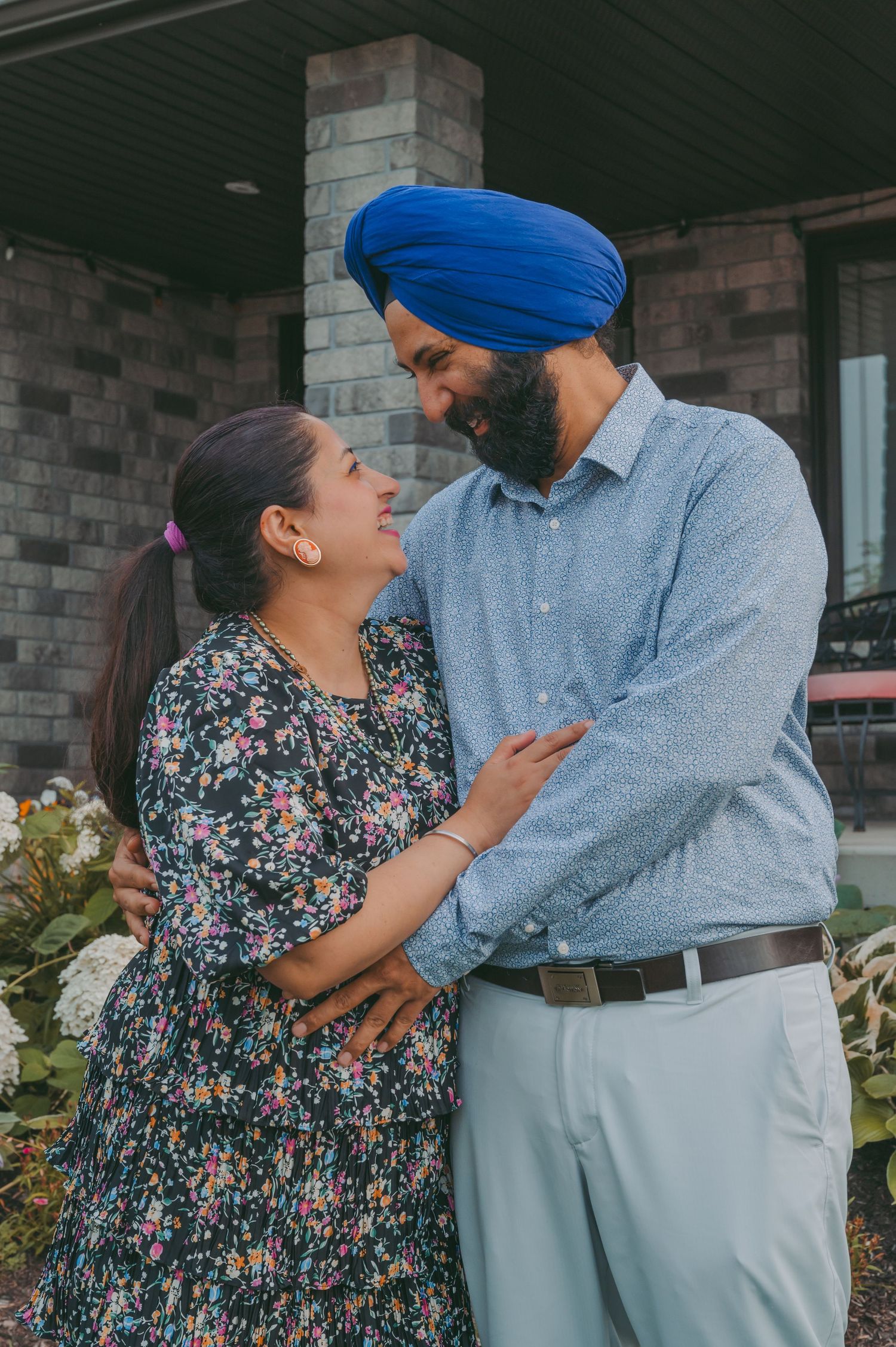 A tender moment shared between two people in casual attire on their porch.