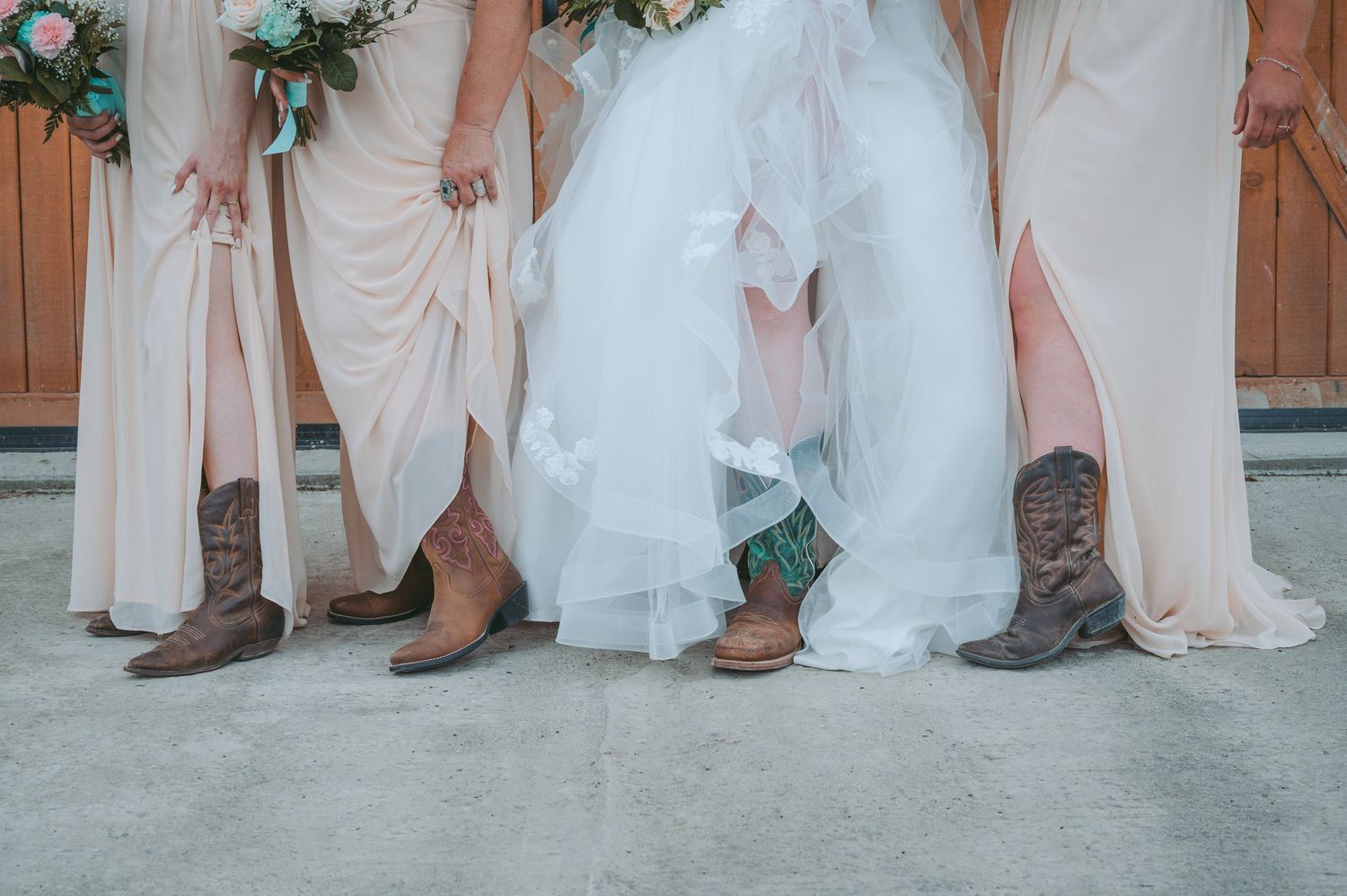 Wedding party members wearing cowboy boots with formal attire stand in a line showing off their footwear.