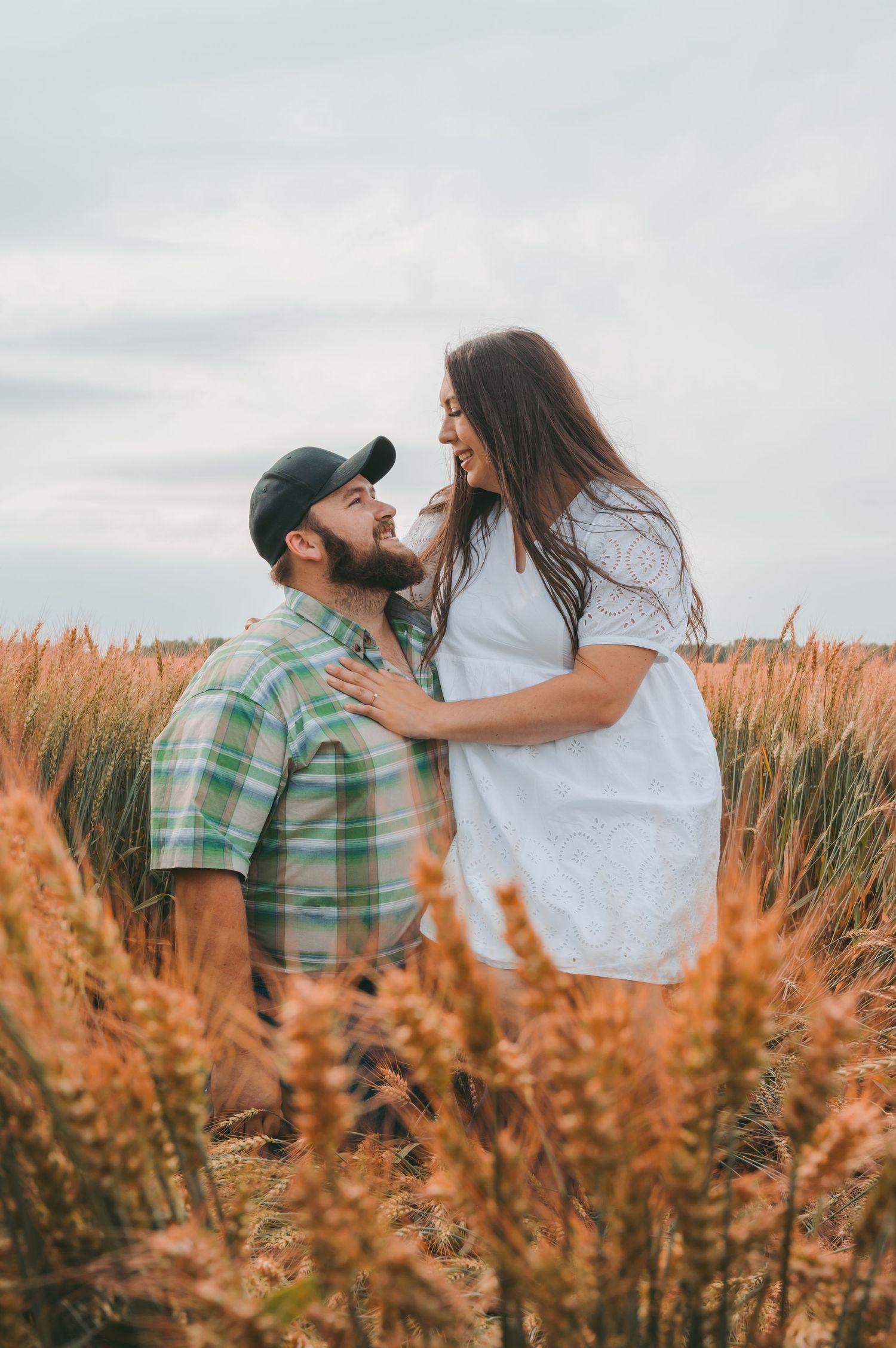 A romantic couple embracing in a golden wheat field at sunset with soft lighting and dreamy atmosphere.