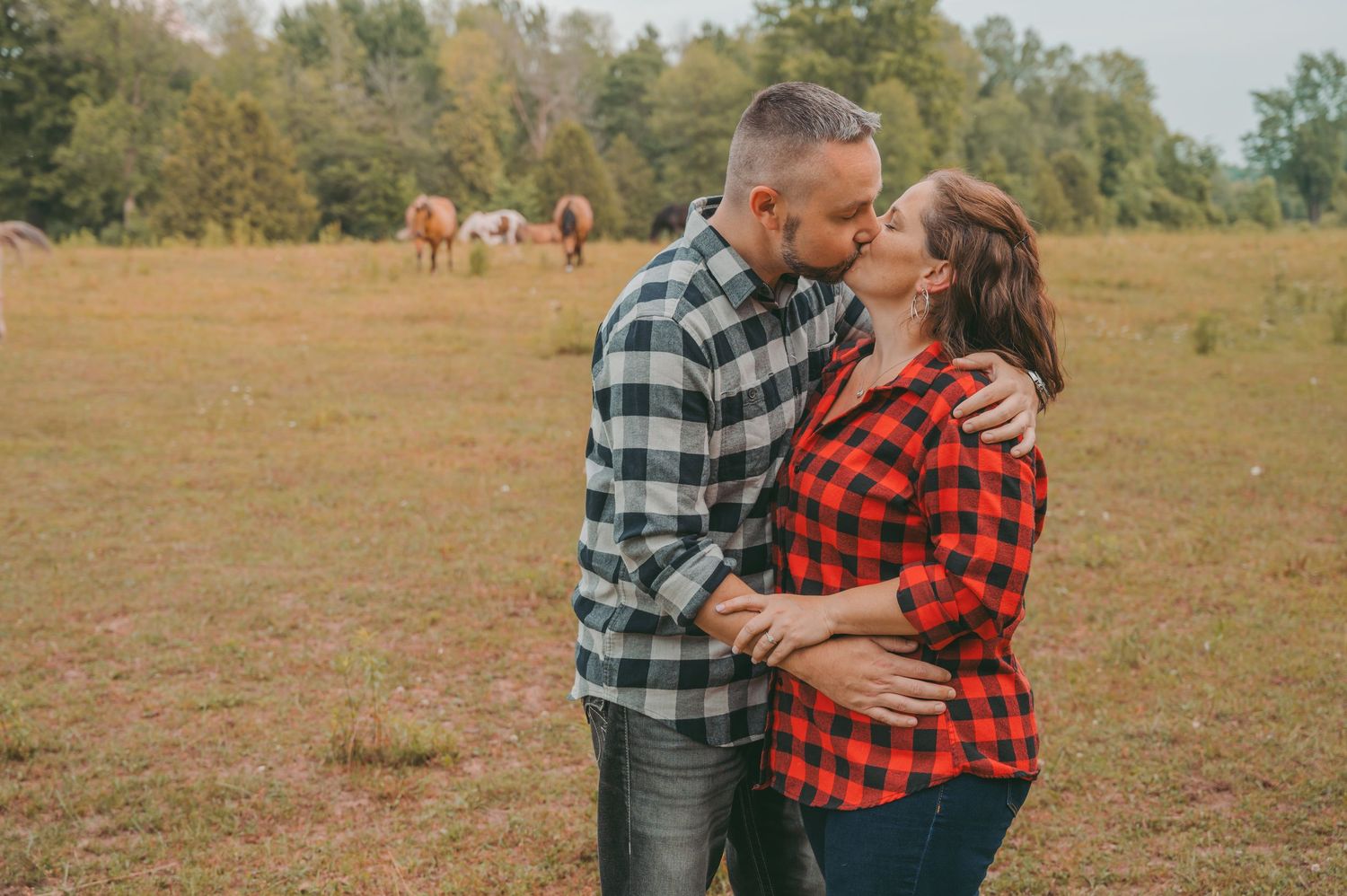 A romantic moment between partners wearing matching plaid shirts in a meadow.