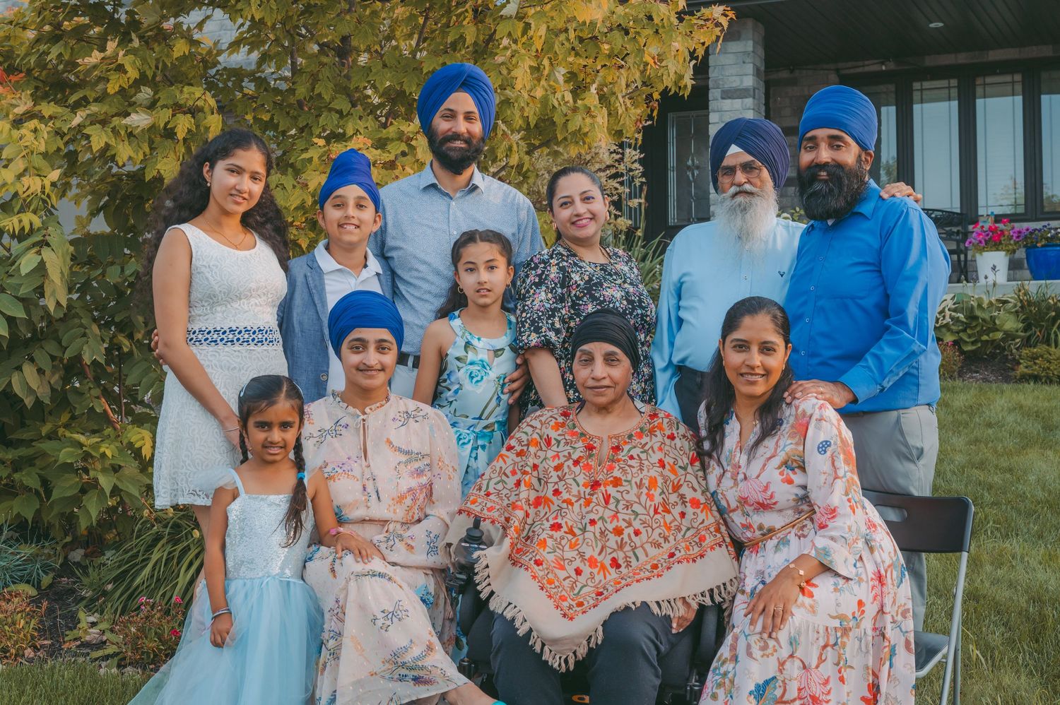 A multigenerational family gathering outdoors with trees in the background.