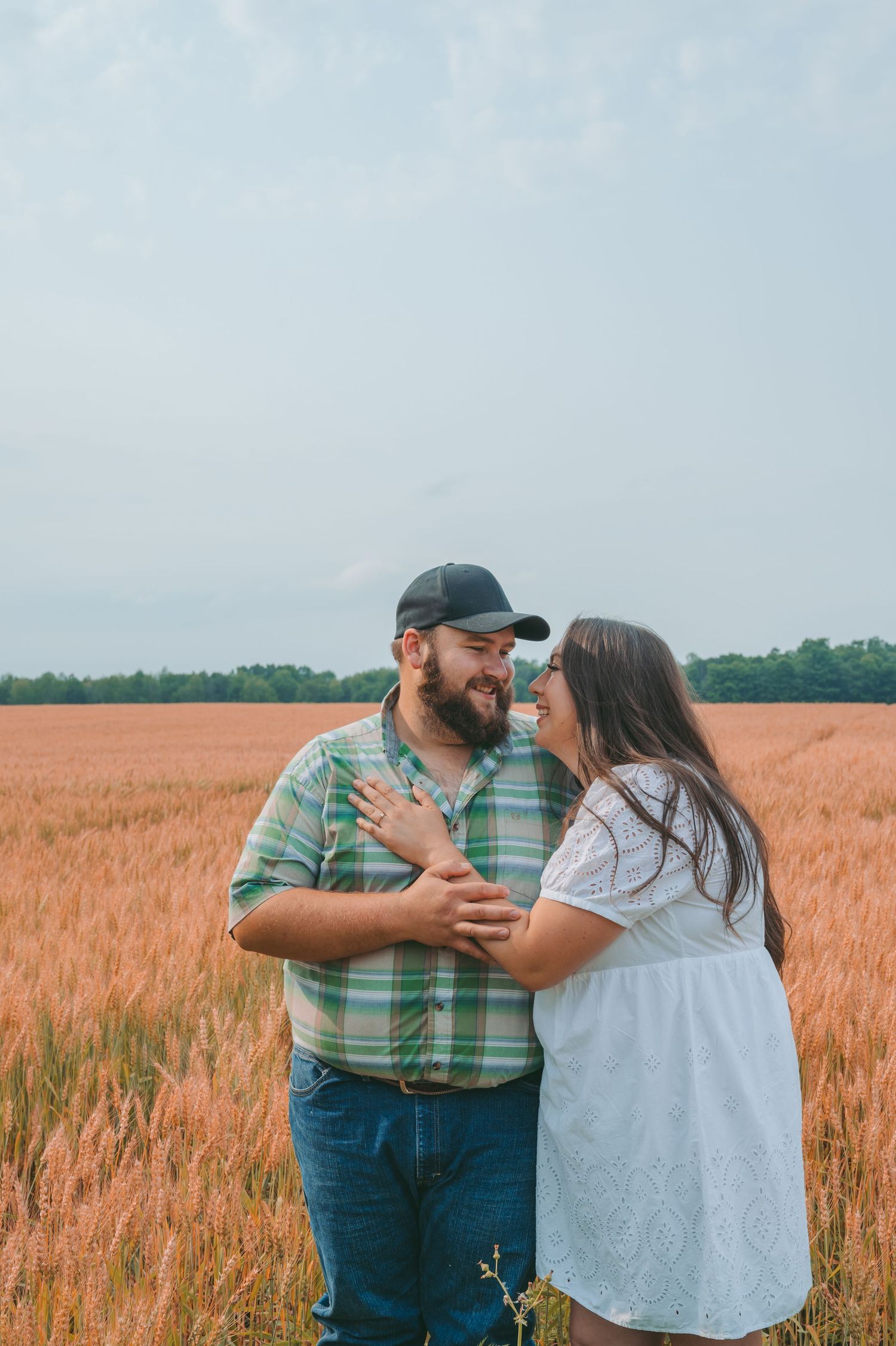 A tender moment between partners in a sunlit wheat field.