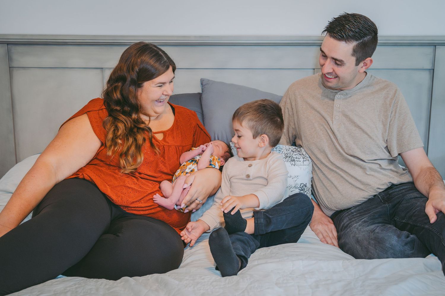 A tender family moment shared on a bed with an infant.