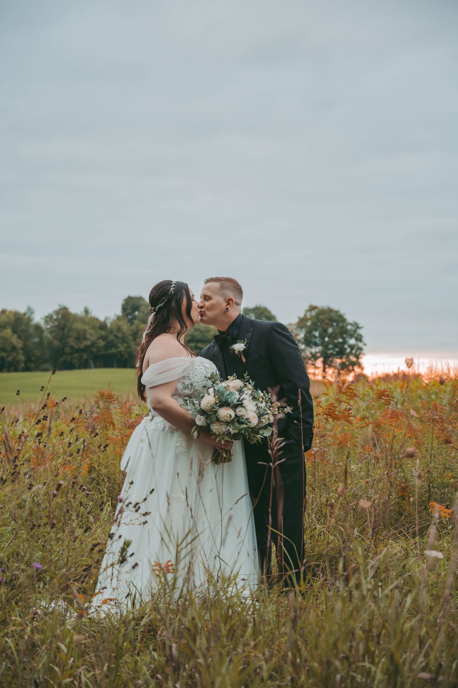 A romantic wedding couple embraces in a golden wildflower field at sunset, creating a dreamy outdoor portrait series.
