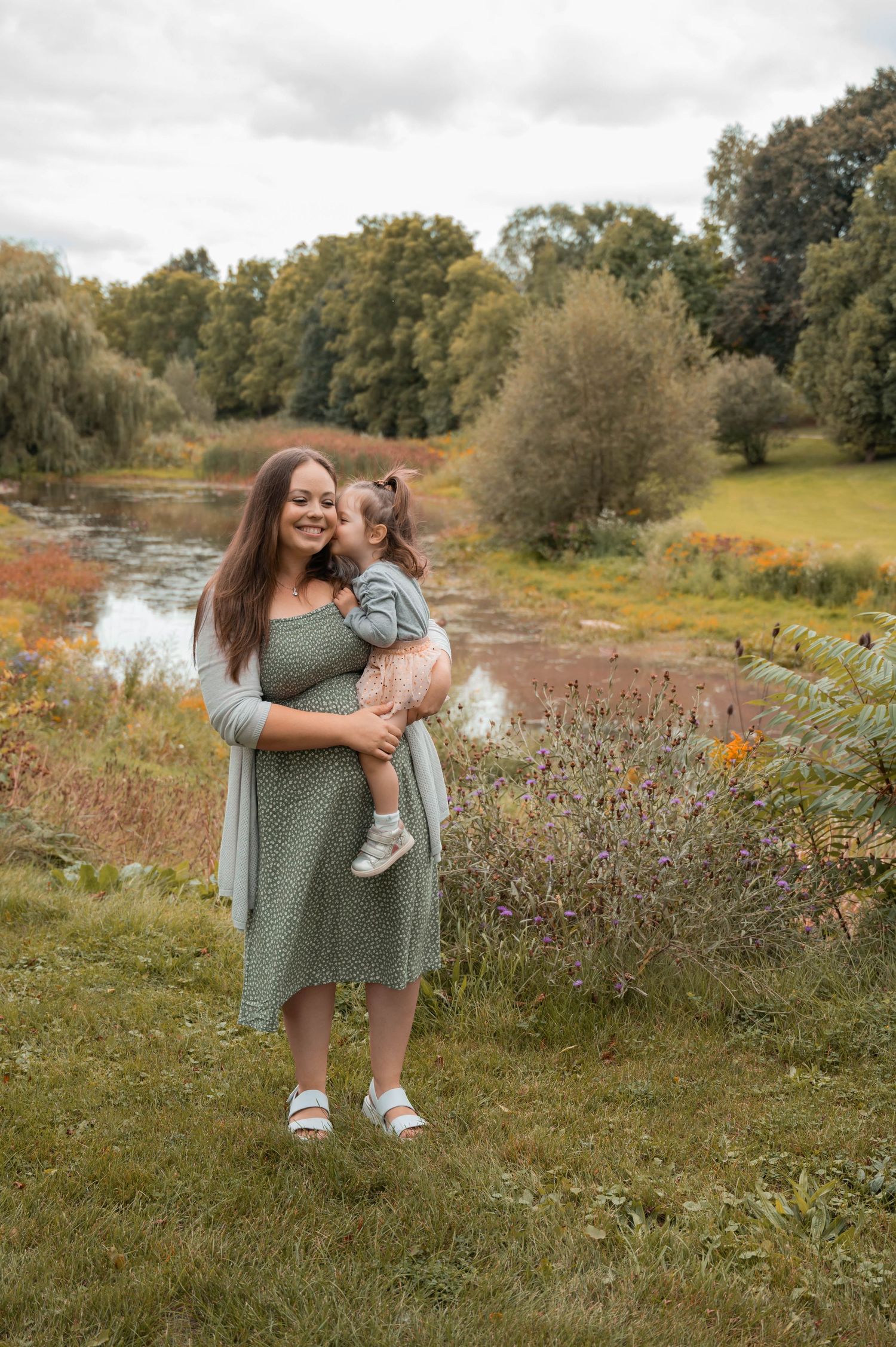 A heartwarming moment between two people enjoying nature by a winding stream in fall foliage.