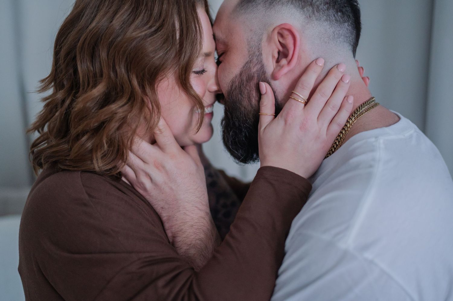 A couple shares a tender romantic moment, gently holding each other's faces as they lean in for a kiss.
