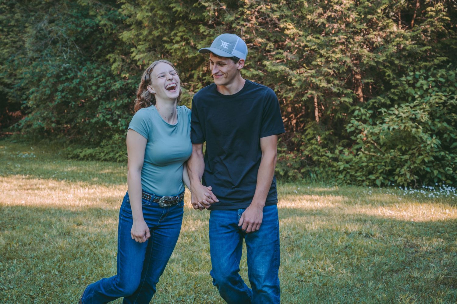 A tender moment shared between a couple laughing together in a sunny garden setting.