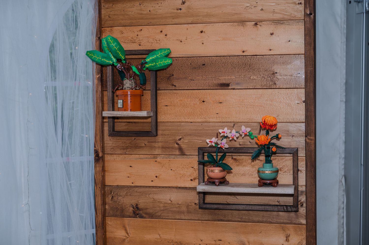 Wooden wall with mounted shelves displaying Lego potted plants and decor items against rustic paneling.