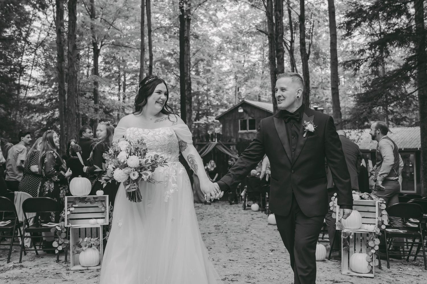 A wedding ceremony takes place in a serene outdoor garden setting with guests seated on white chairs.