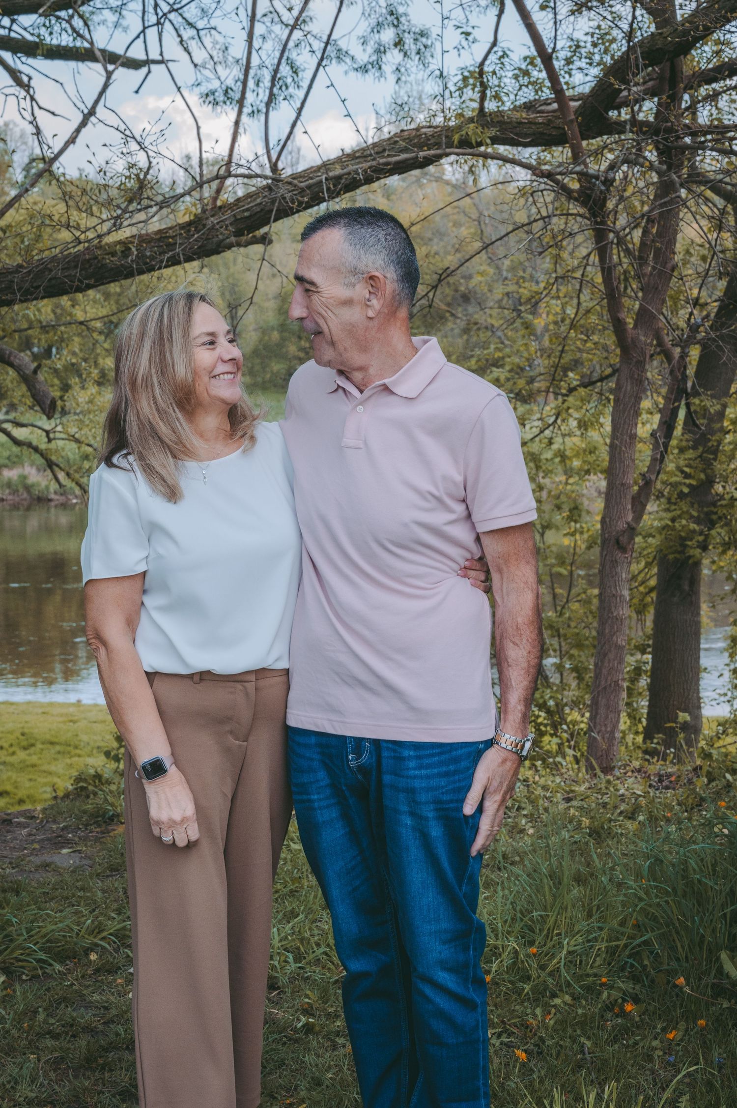 Couple in casual attire sharing loving moment by lakeside.