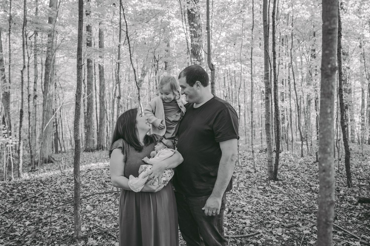 Black and white capture of family bonding together in peaceful forest environment.