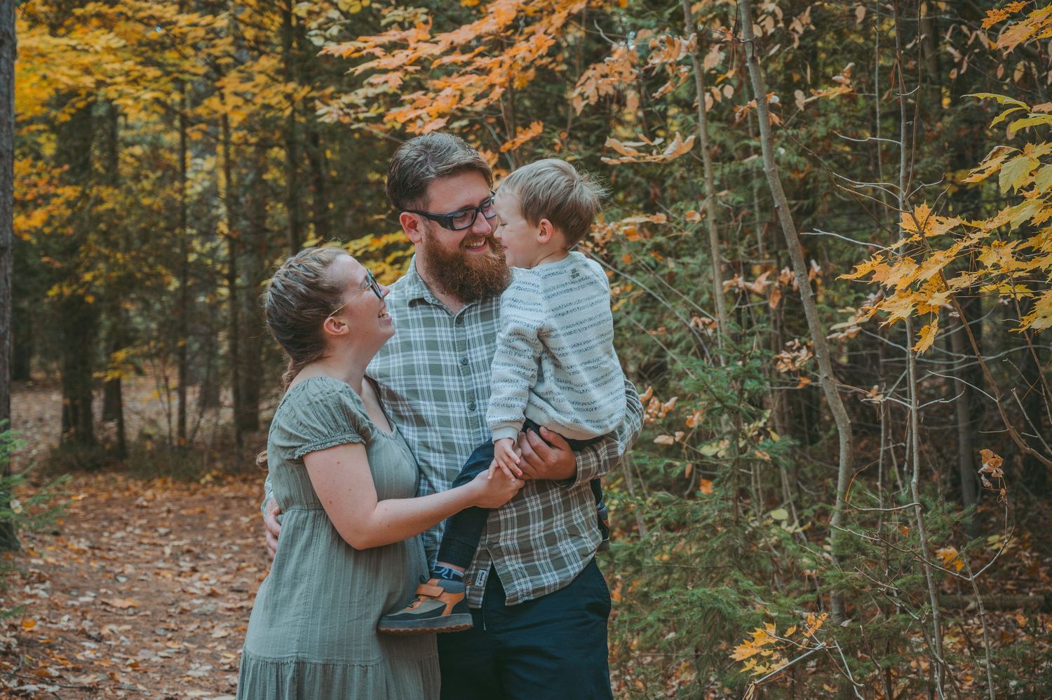 Intimate family moment captured in forest setting with golden fall colors.