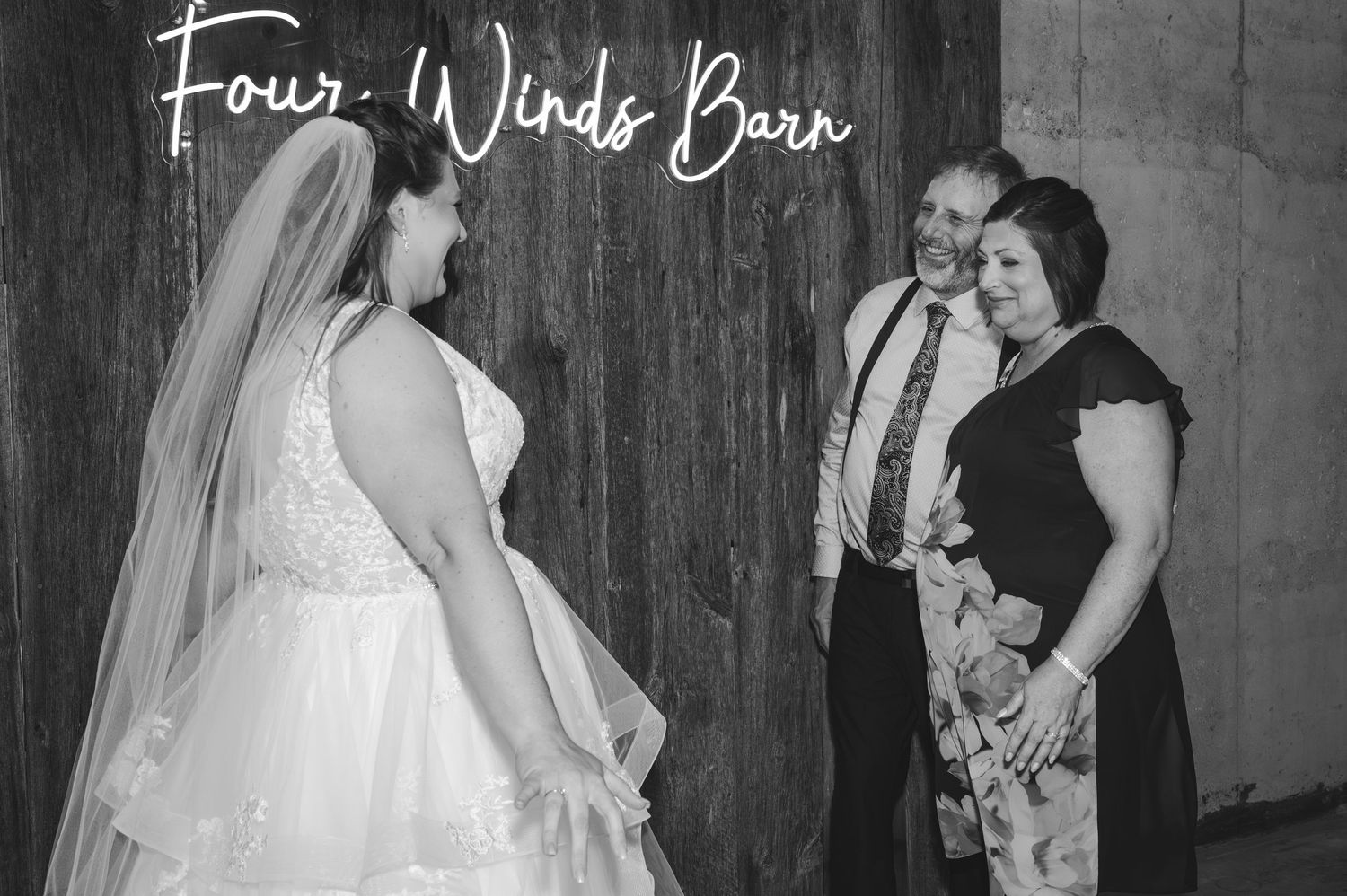 Black and white photo of a family interaction in front of a wooden wall.