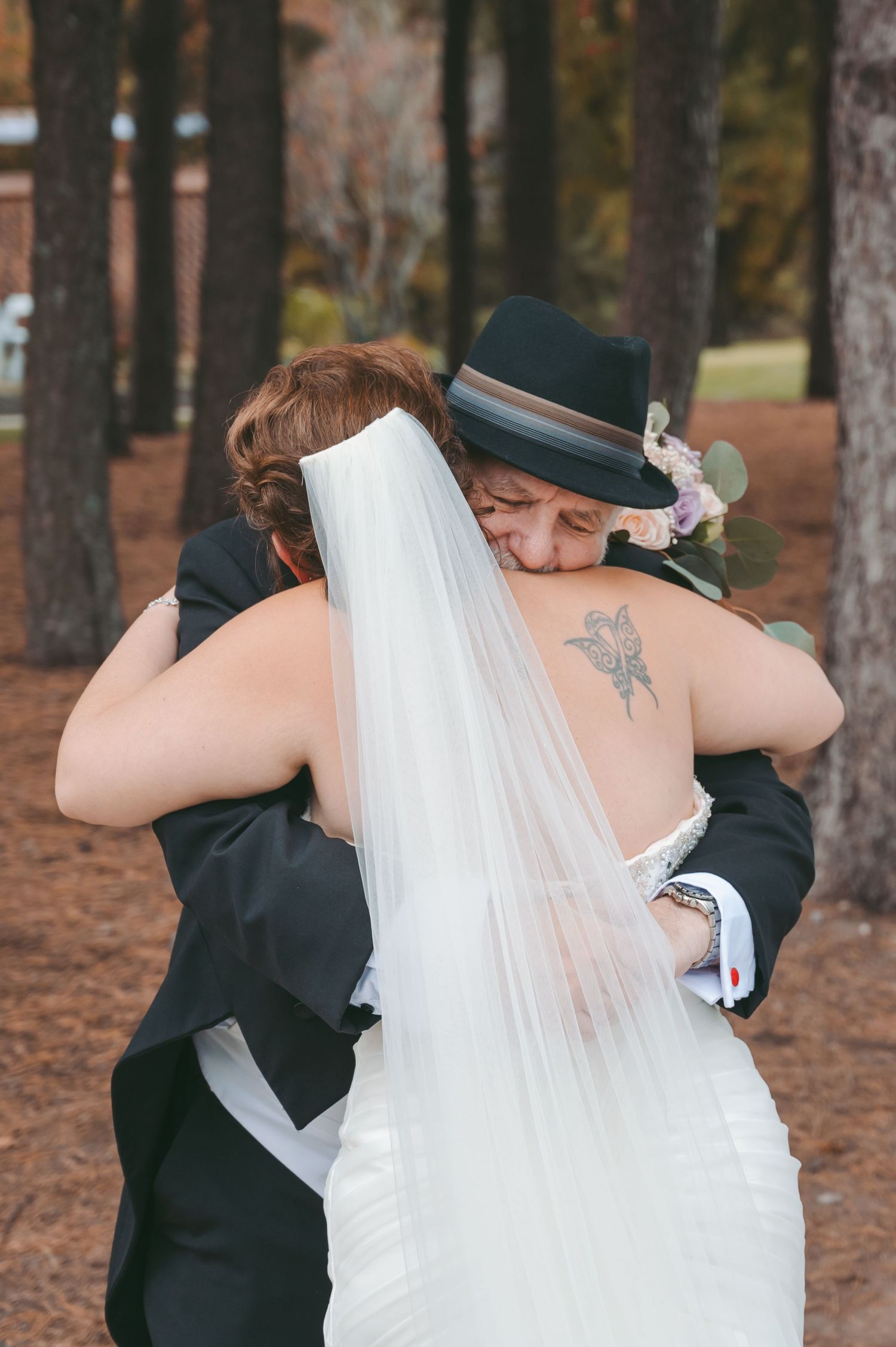 An intimate embrace between two people during an outdoor fall wedding.