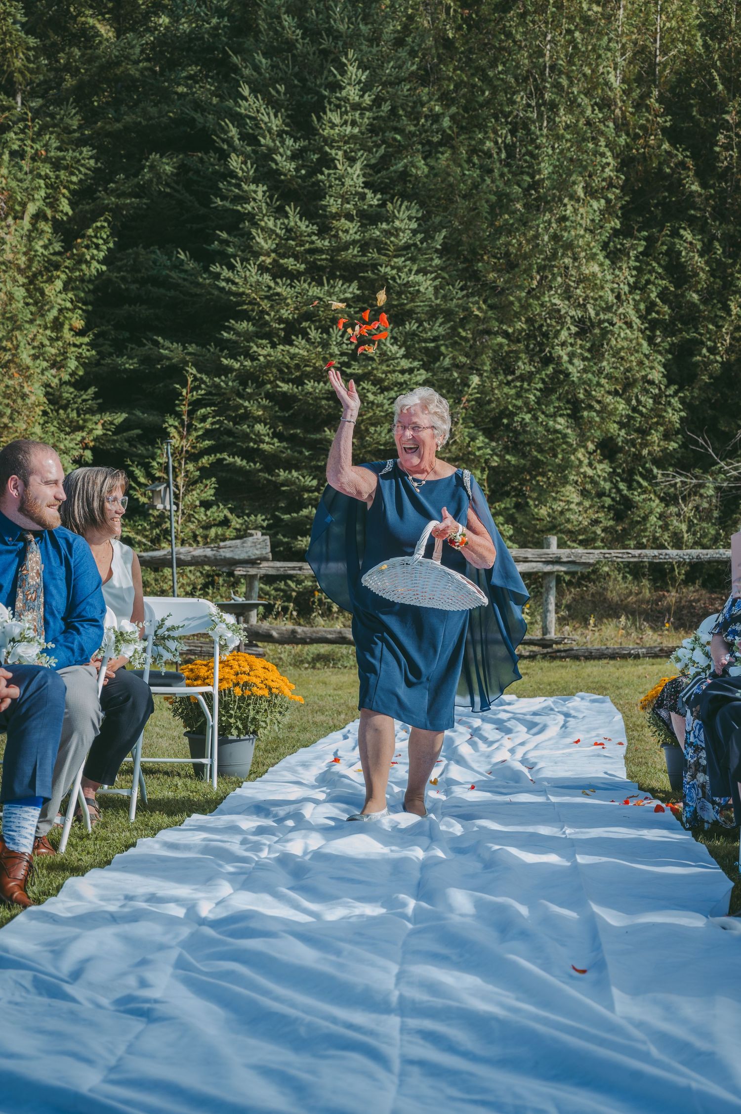 A grandmother walking down the aisle tossing petals.